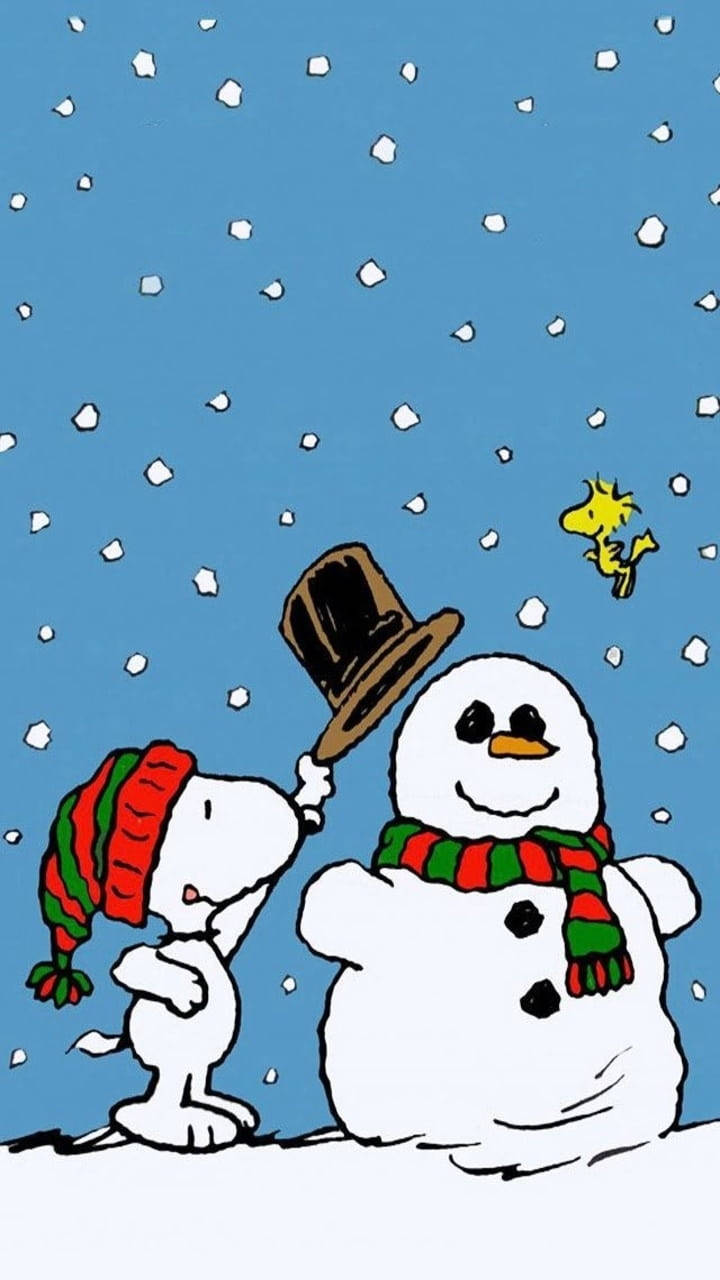 史努比聖誕雪人帽 壁紙 — 史努比戴著紅綠色的帽子，輕輕地將一頂高帽放在雪人上，而胡士托則在附近飛翔，背景是雪白的藍天。