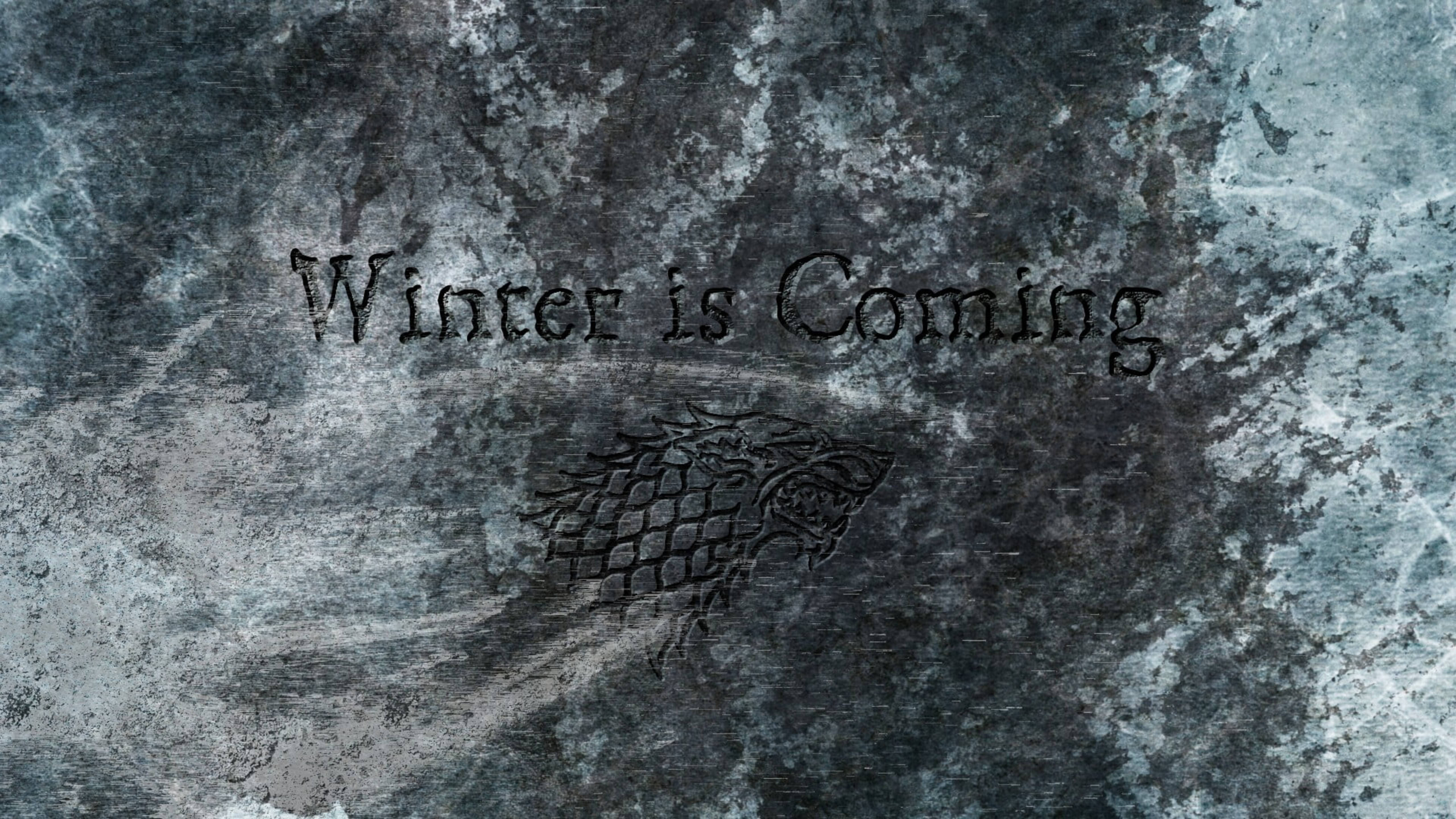 史塔克家族雕刻灰狼圖騰 壁紙 — 史塔克家族冰原狼徽章及「Winter is Coming」字句刻在冰藍與灰色質感的冰石上。