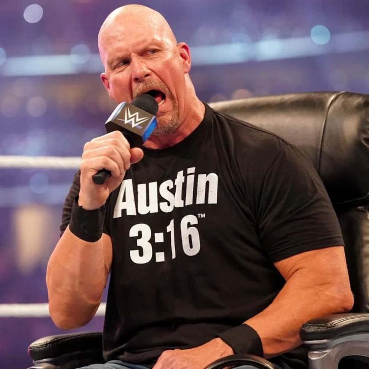 摔角手 Austin 3:16 坐在擂台內的椅子上，對著 WWE 麥克風大喊。