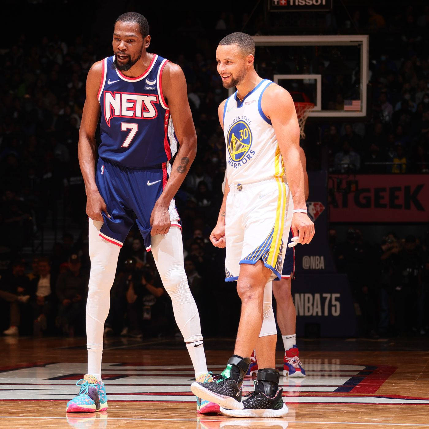 史蒂夫·庫里與凱文·杜蘭特 壁紙 — 兩名身穿球隊制服嘅NBA籃球運動員企喺拋光嘅球場上，背景有觀眾同籃框。