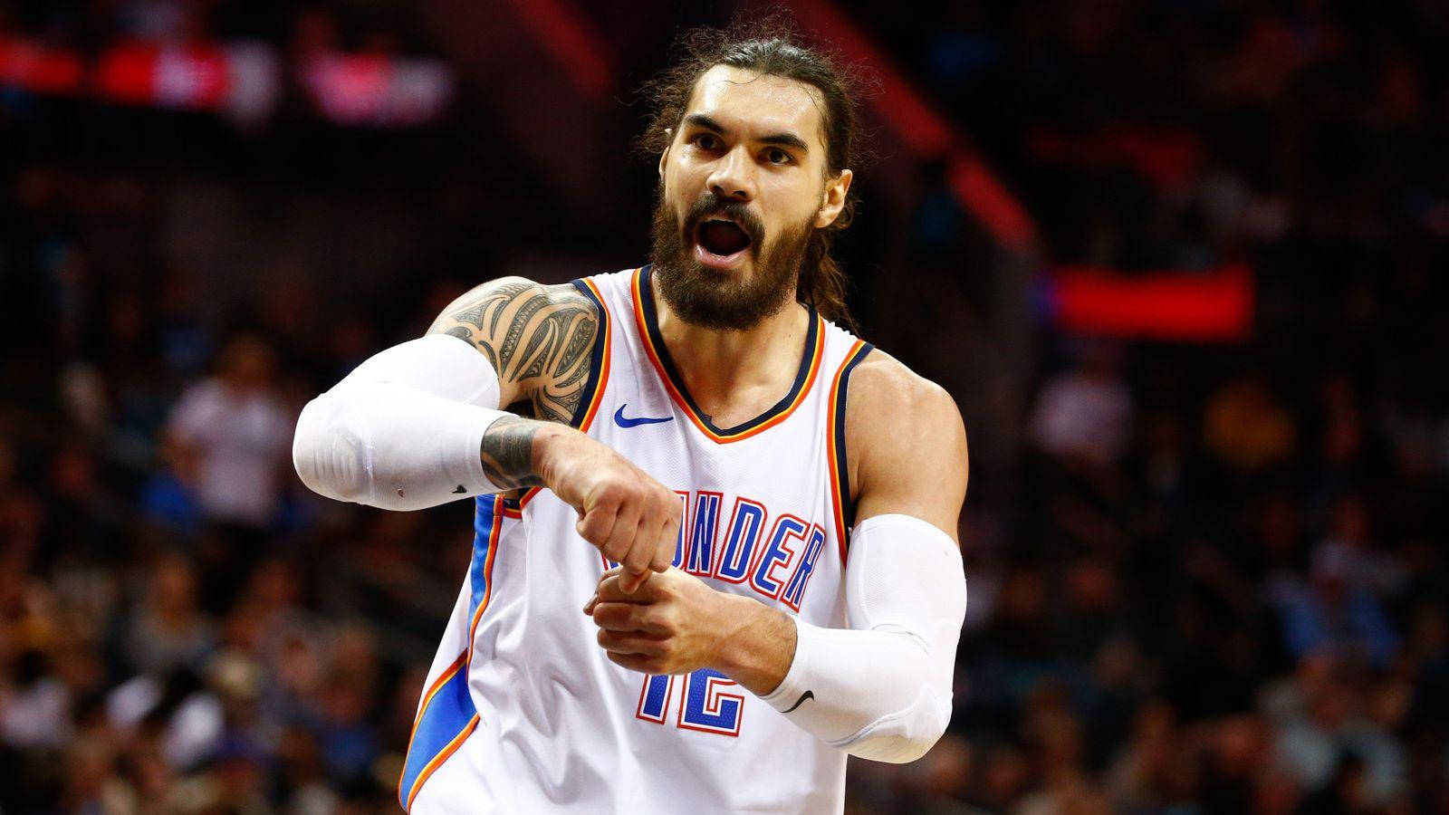 史蒂文·亞當斯 OKC 雷霆隊 中鋒 12號 壁紙 — 一名身穿奧克拉荷馬城雷霆隊球衣的籃球運動員在場館燈光下比賽時激烈地大喊。