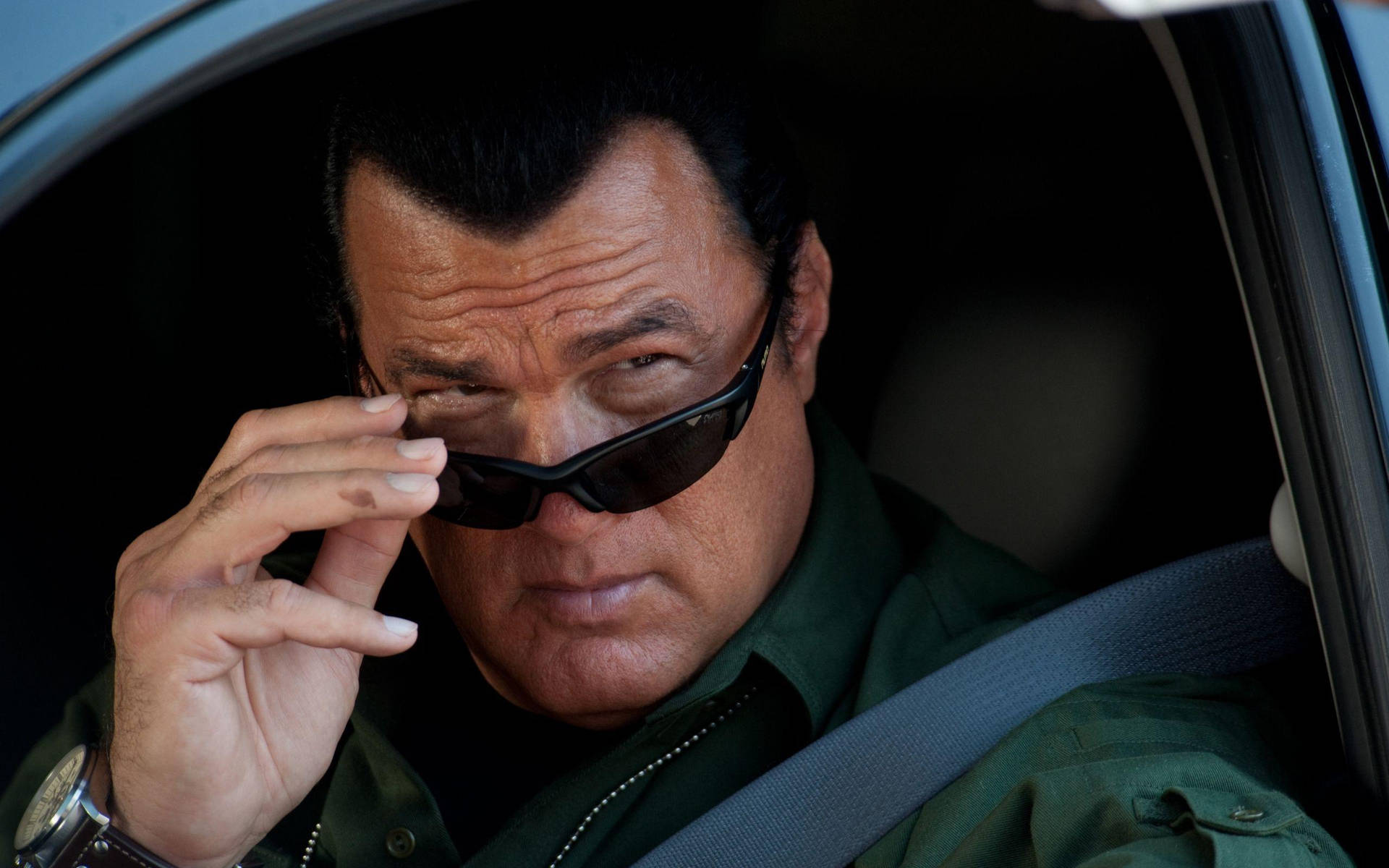 綠色外套男子在車內調整太陽眼鏡