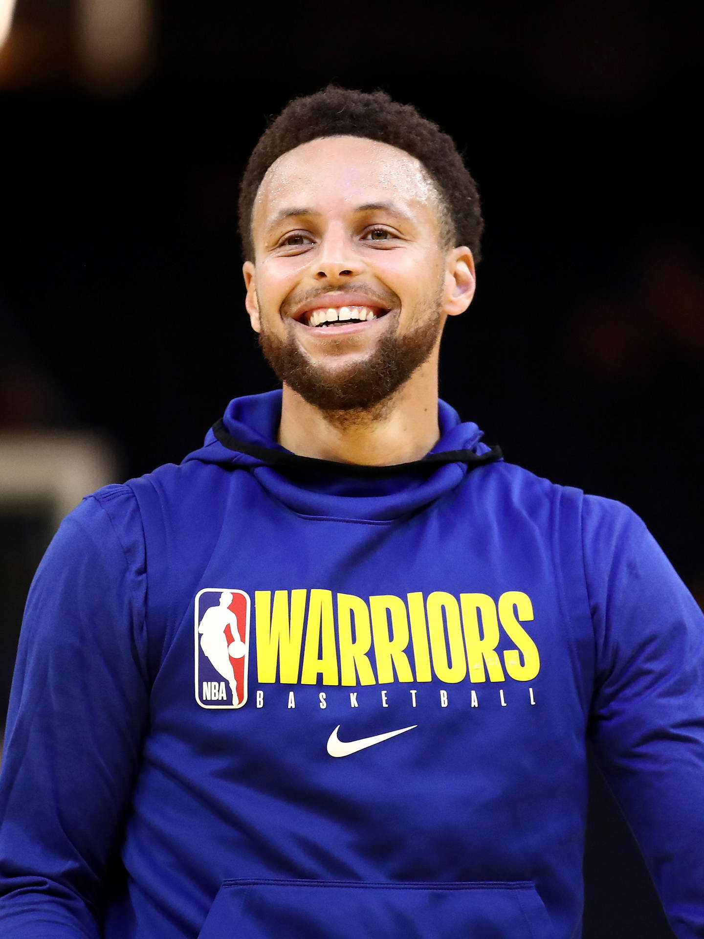 微笑的籃球運動員穿著藍色Warriors連帽衫