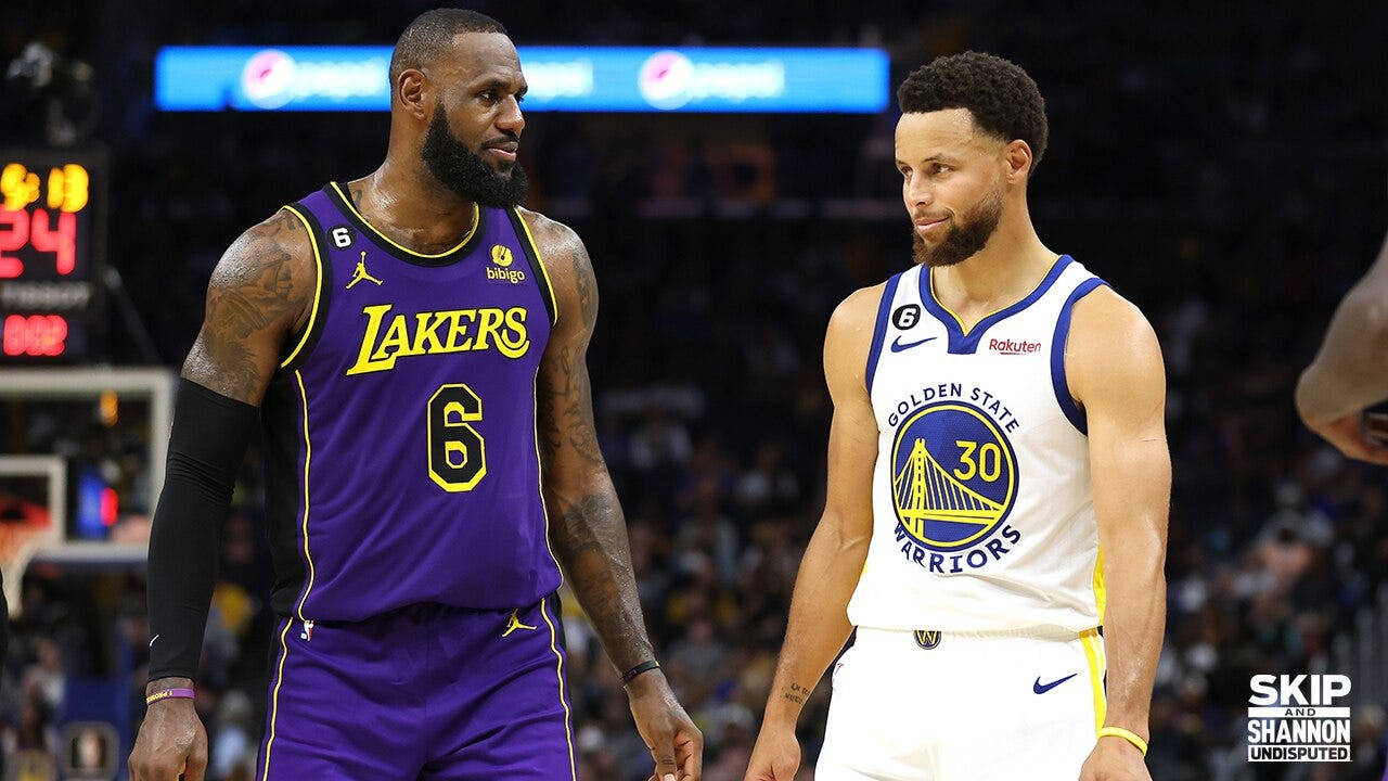史蒂芬·柯瑞與勒布朗·詹姆斯同框 壁紙 — 兩位NBA巨星勒邦占士和史提芬居里在場館燈光下，穿著球隊球衣於一場高風險比賽中對決。