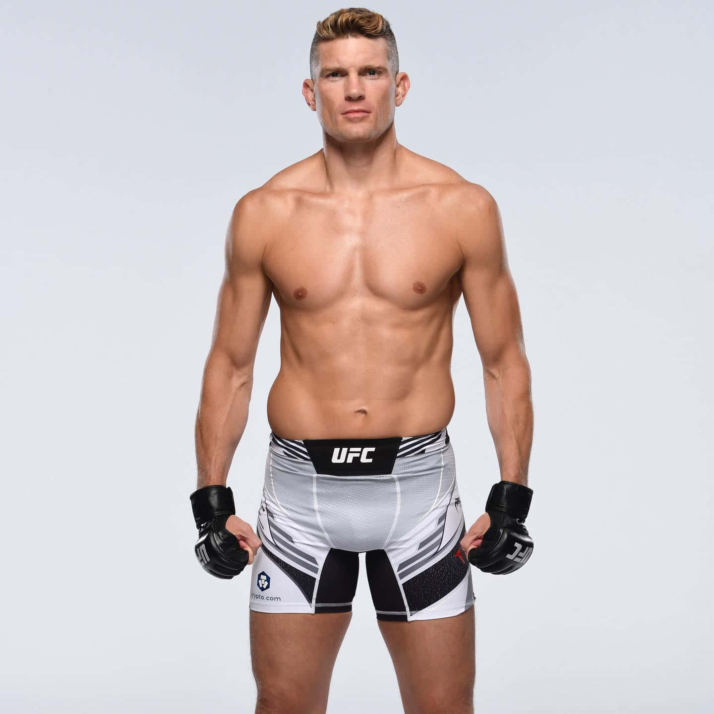 一位赤裸上身的男性綜合格鬥選手穿著UFC裝備為照片擺姿勢。
