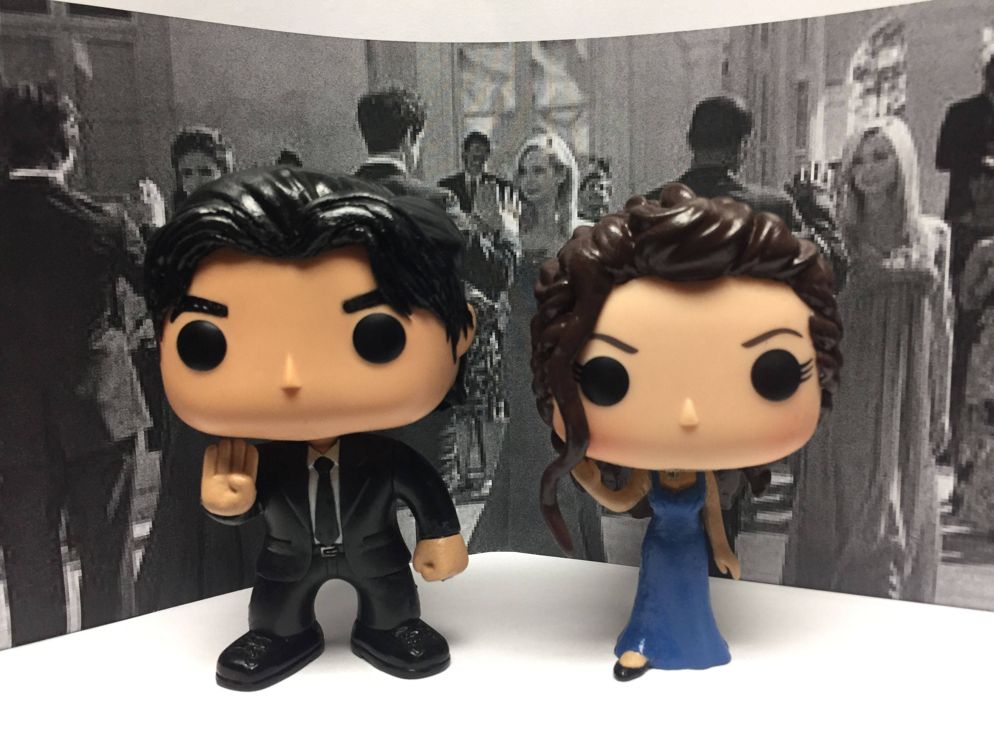 史蒂芬·薩爾瓦托與艾蓮娜 Funko Pop 壁紙 — 兩個 Funko Pop 人偶站在黑白電影海報背景前，背景為人群場景。