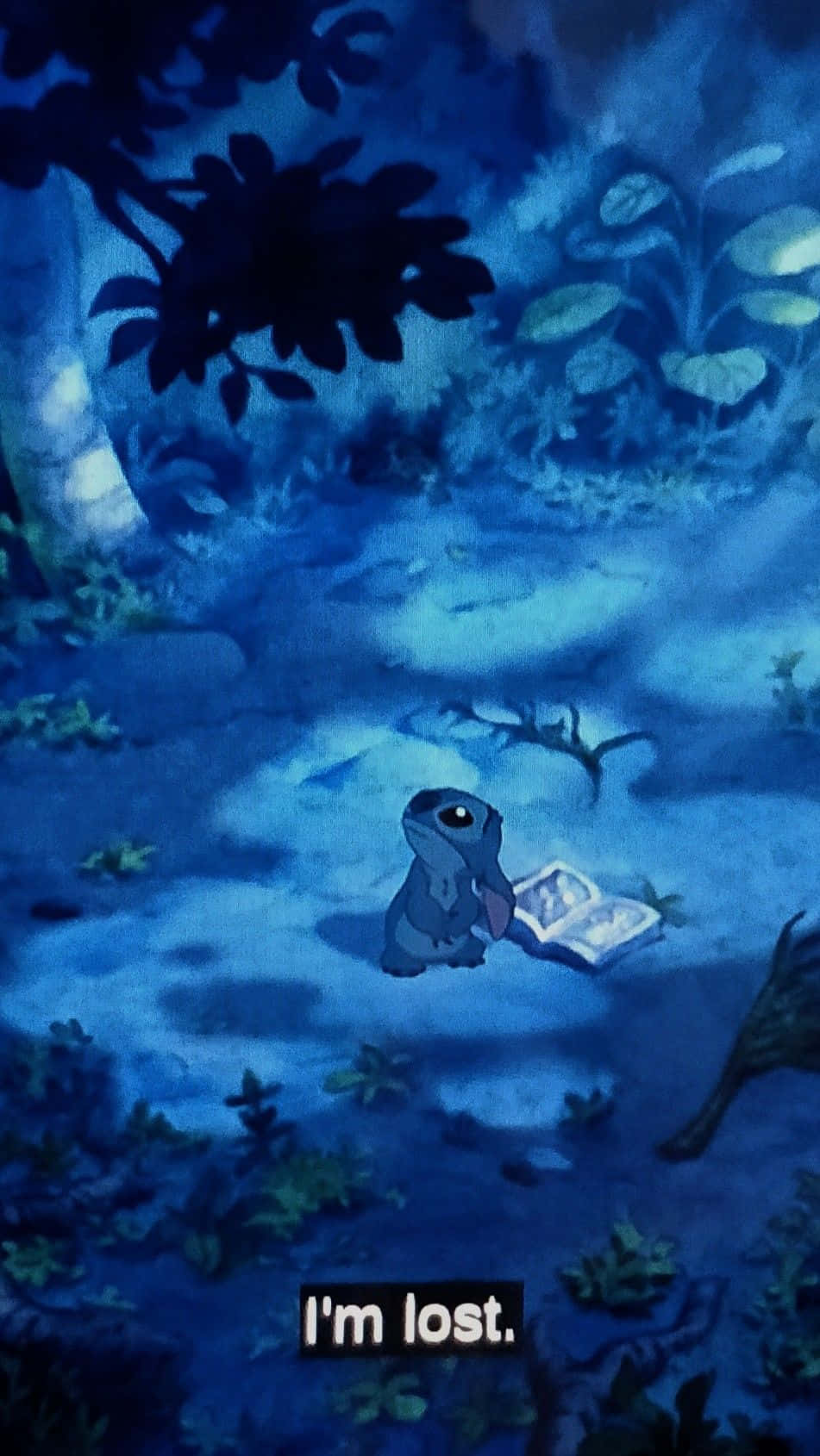 一個藍色外星人坐在黑暗的叢林中，拿著一本發光的書，看起來迷失。