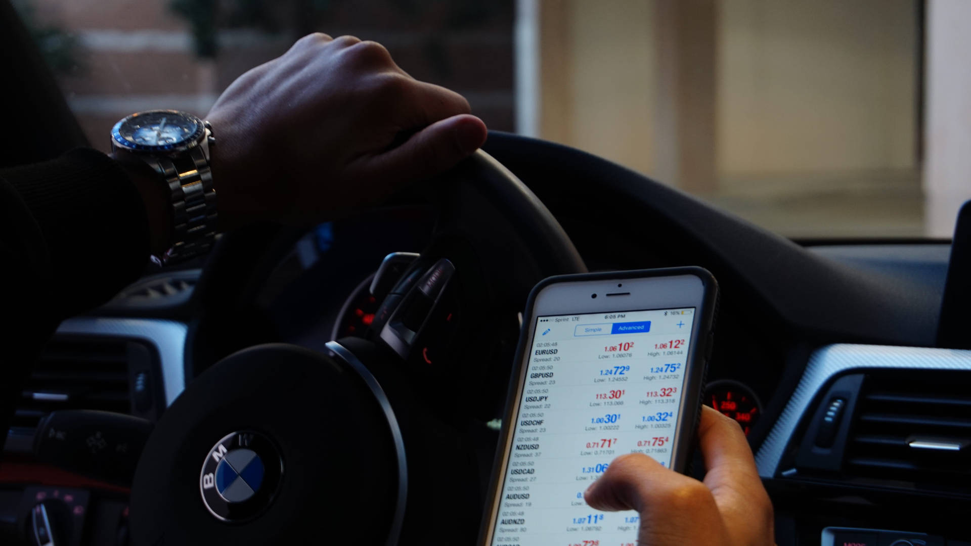 錢 桌布 壁紙 — 司機的手握著BMW軚盤，另一隻手則拿著顯示叫車應用程式及車費估算的電話。