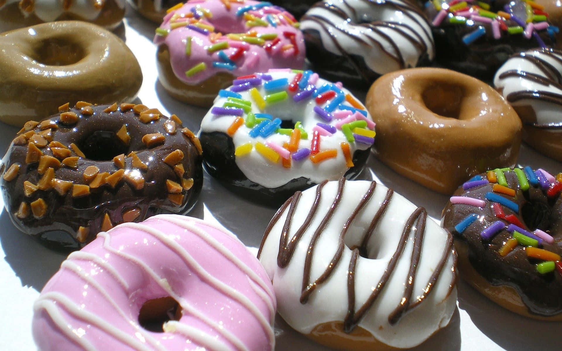 donuts 桌布 壁紙 — 各種有彩色糖粒和朱古力醬的糖霜裝飾冬甩的近距離特寫。