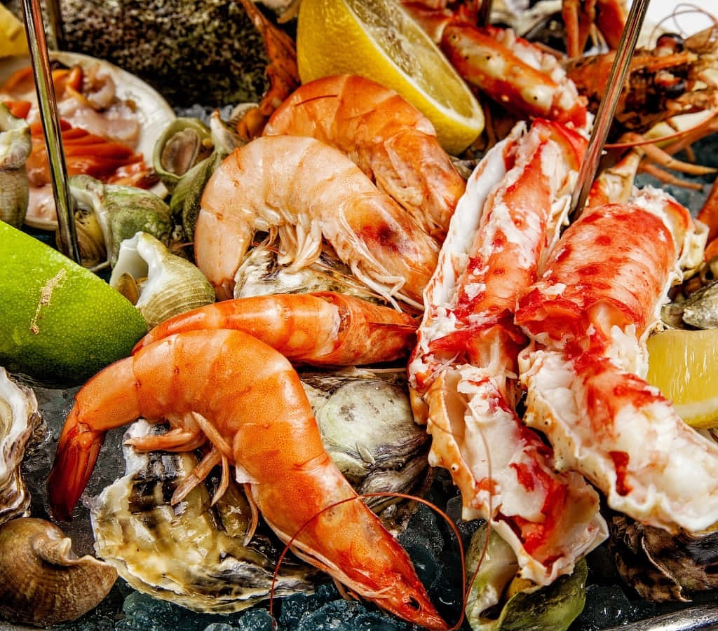 Seafood 桌布 壁紙 — 各種燒烤海鮮嘅鮮豔近鏡，包括蝦、蟹腳同生蠔，用檸檬同青檸角裝飾。