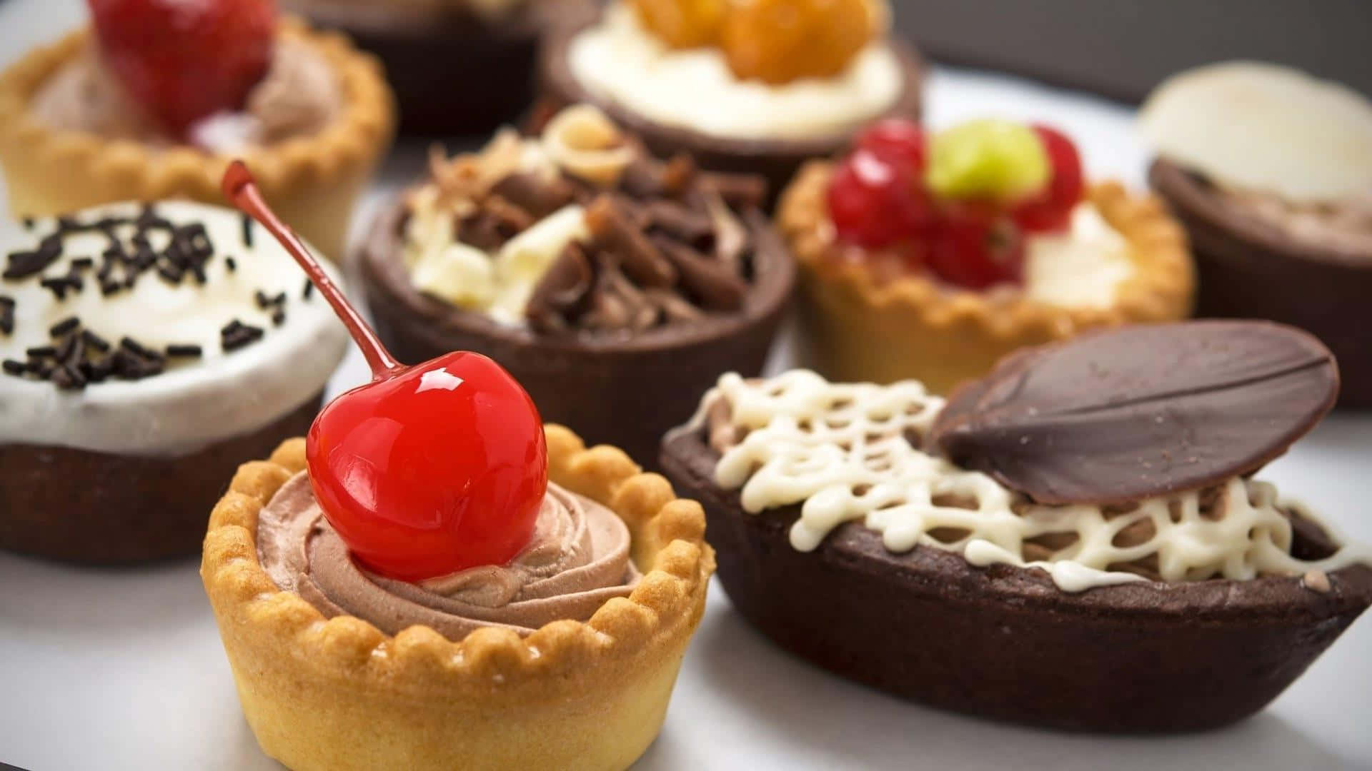 Bakery 桌布 壁紙 — 各種精緻迷你撻的特寫，上面放有櫻桃、朱古力碎和新鮮漿果。