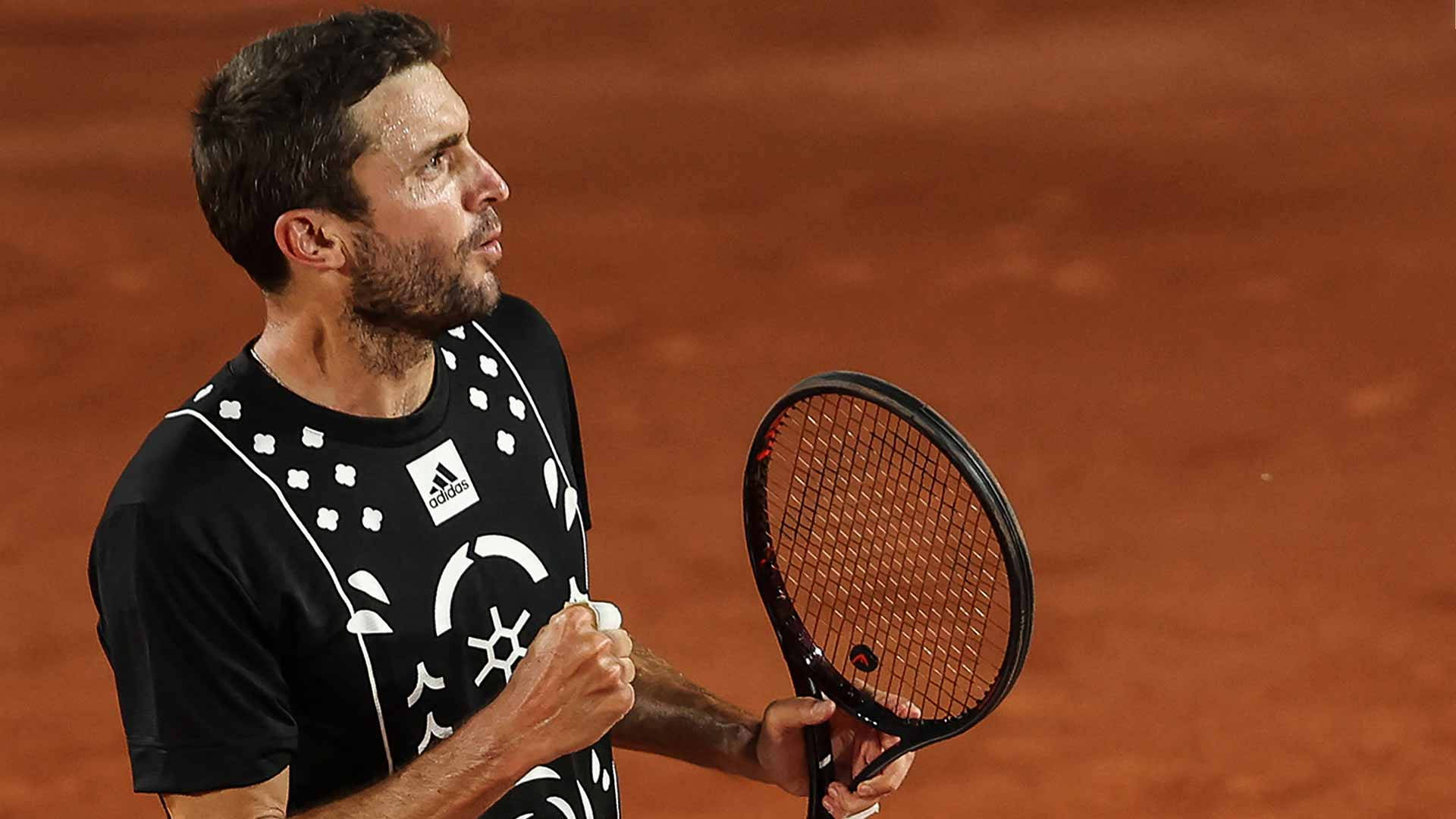 網球選手在紅土場上握拳慶祝勝利。