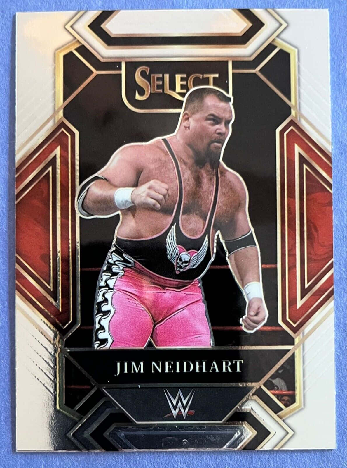 吉姆·尼德哈特圖形設計 壁紙 — WWE摔角手Jim Neidhart穿著粉紅色短褲和黑色背心，在幾何框架的收藏卡內咄咄逼人地擺姿勢。