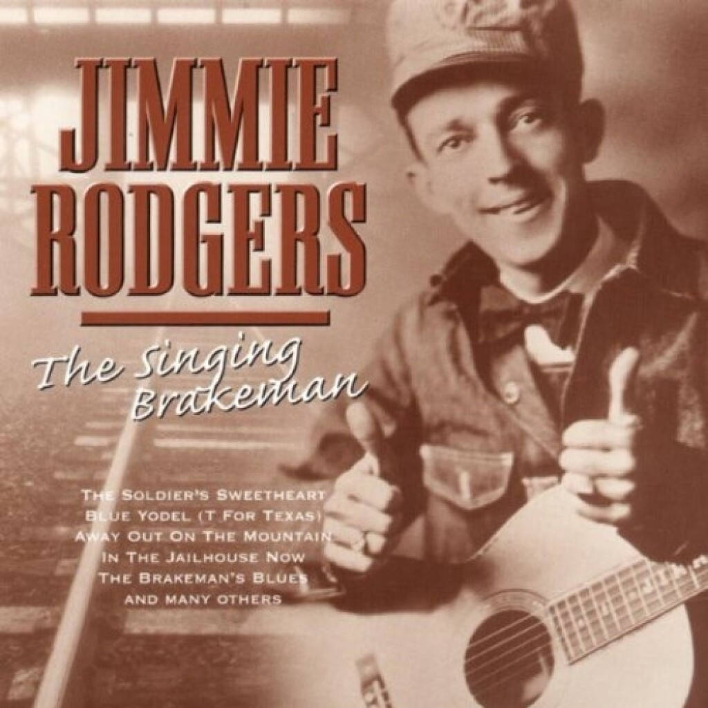 吉米·羅傑斯——歌唱的火車司機 壁紙 — Jimmie Rodgers 微笑著抱著木結他並豎起兩個大拇指的復古棕褐色肖像。