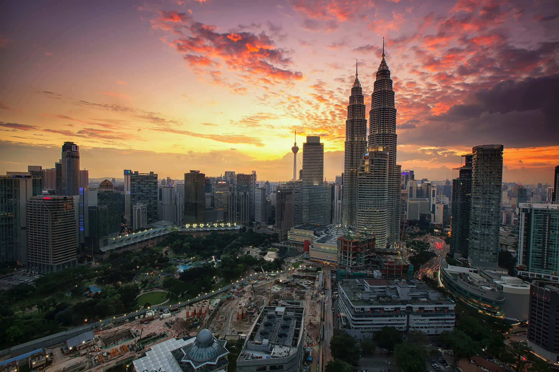 Malaysia 桌布 壁紙 — 吉隆坡天際線在日落時的鳥瞰圖，雙子塔在火熱的橙色和紫色雲層中閃耀。