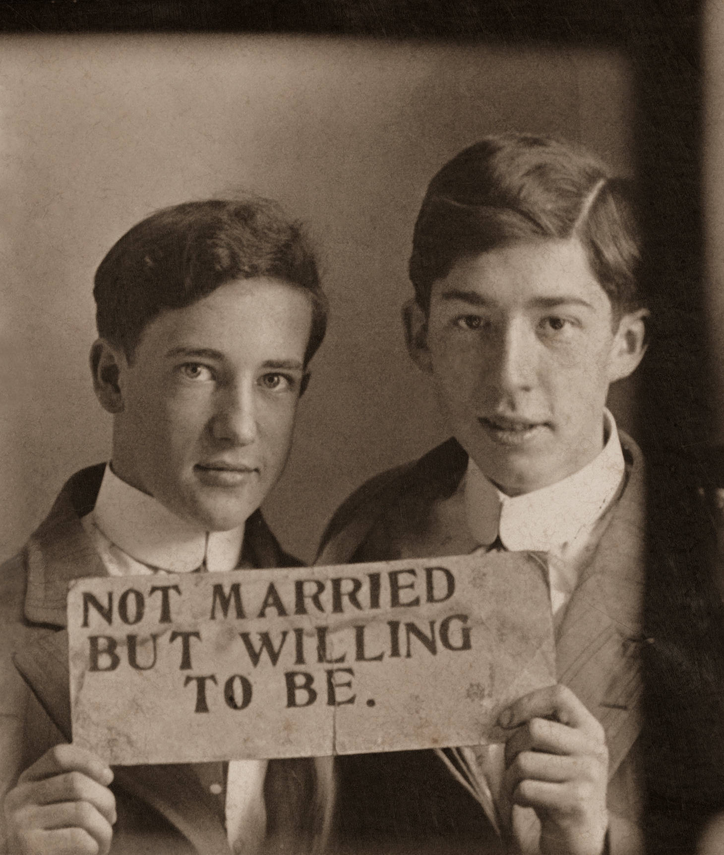 兩位穿西裝的男子手持寫有not married but willing to be的標語牌