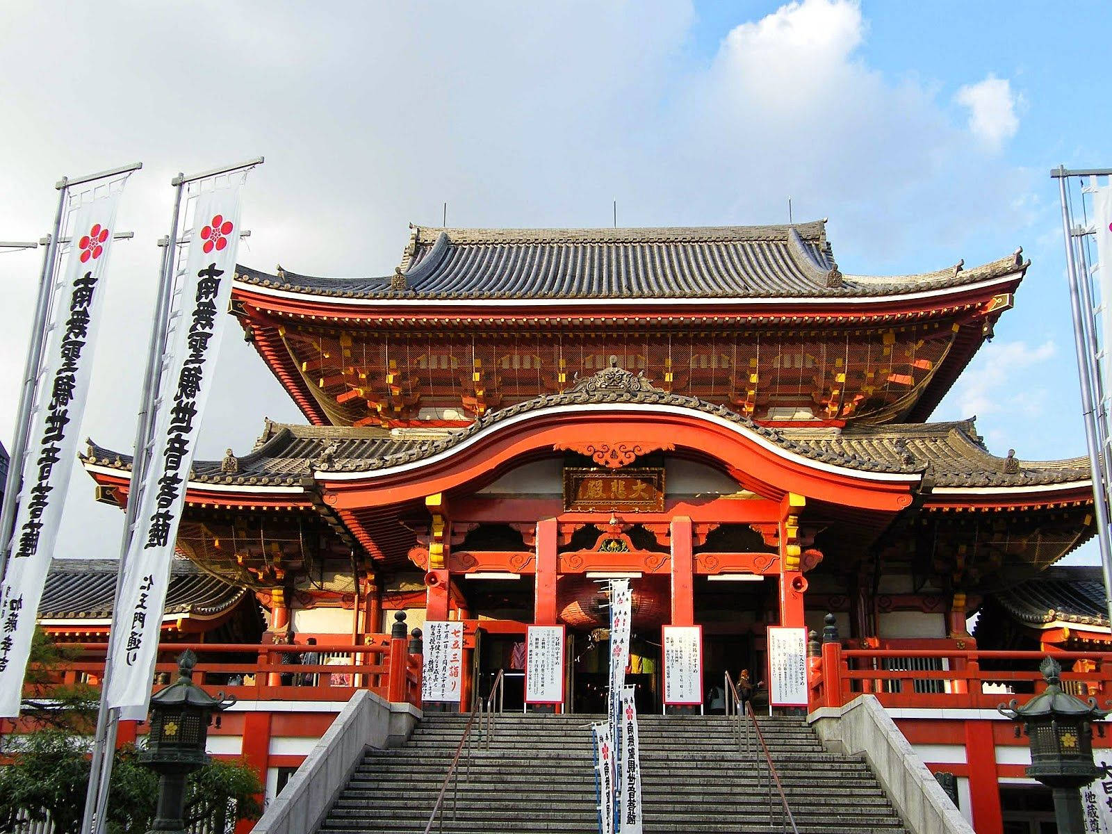 名古屋大須觀音紅寺 壁紙 — 在部分多雲的天空下，擁有寬闊瓦頂和石階的大型紅色日本神社。