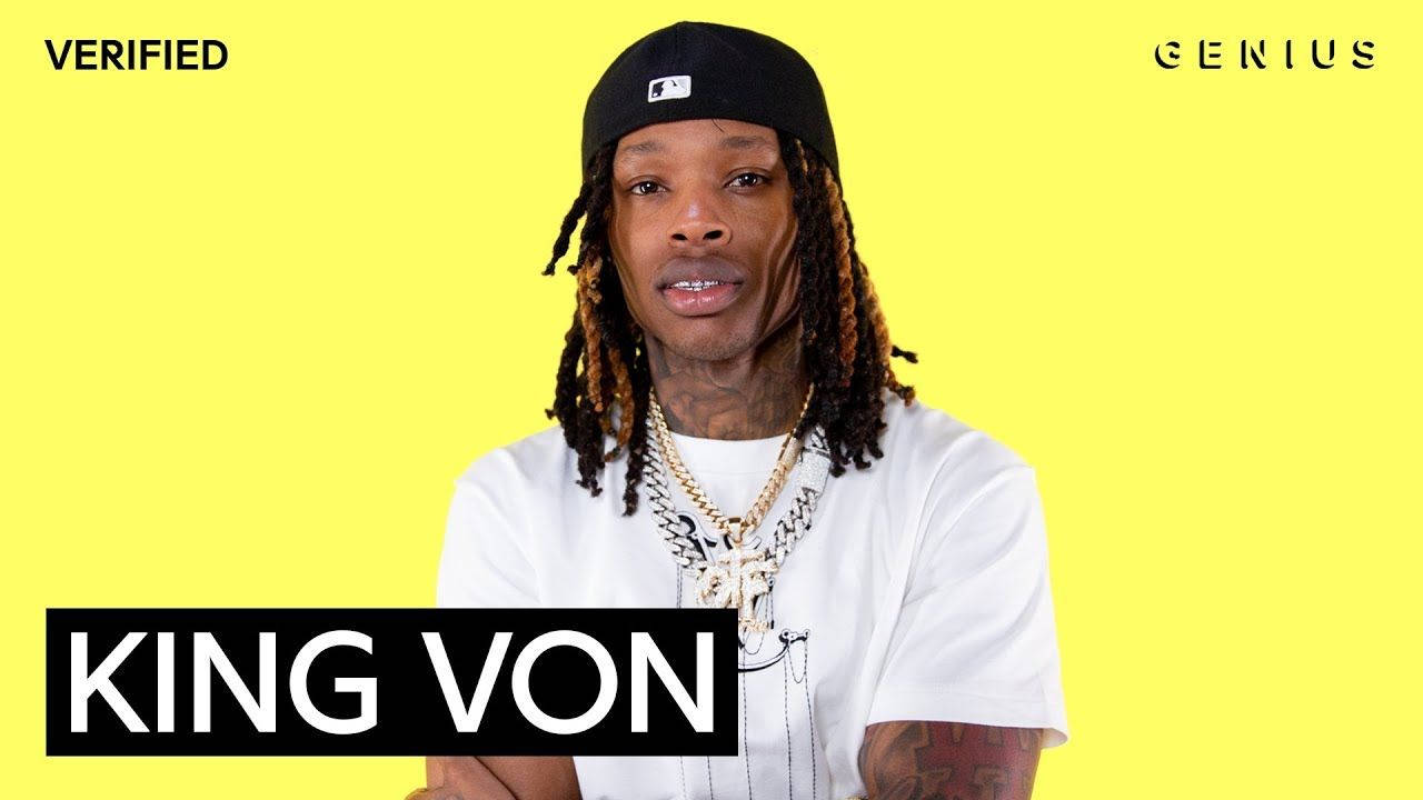 向 King Von 的遺產致以深情致敬 壁紙 — King Von 在明亮的黃色背景前自信地擺姿勢，戴著黑色帽子和金鏈。