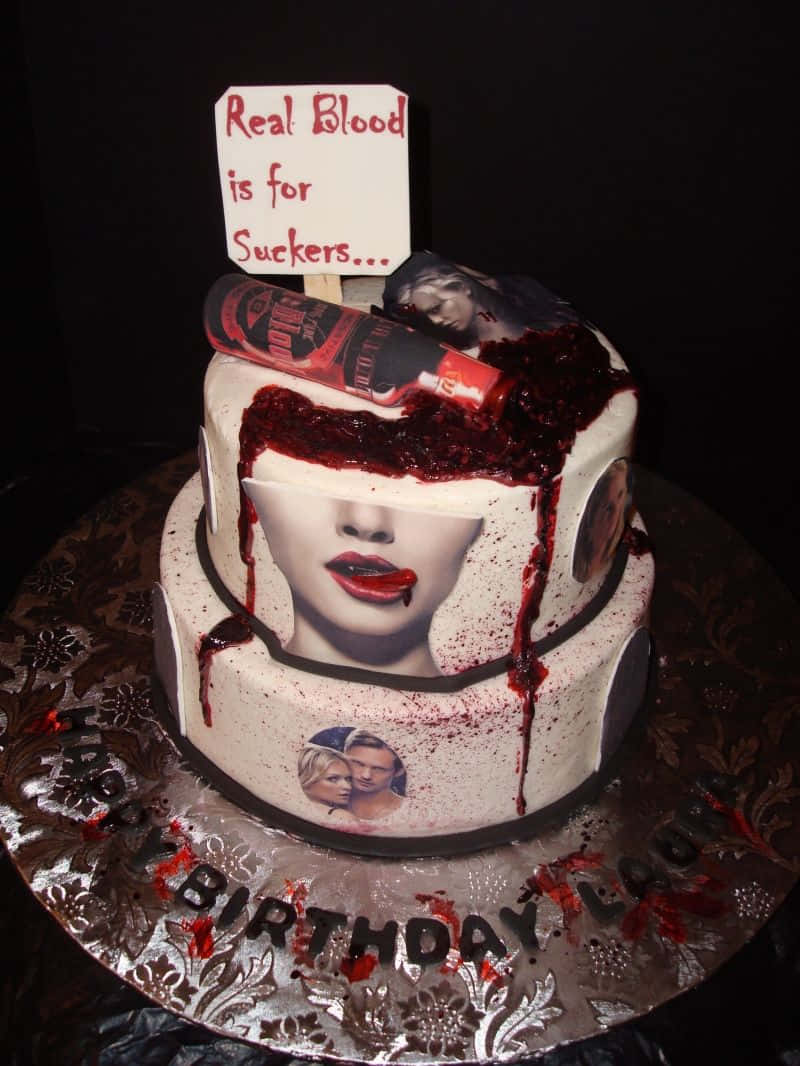 一個吸血鬼主題的生日蛋糕，有紅色糖霜、一個血瓶和一個寫著「Real Blood is for Suckers」的標誌。