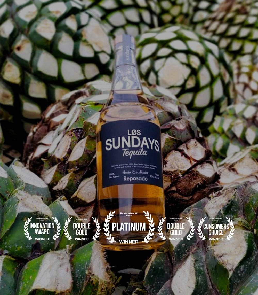 味覺勝利——Los Sundays龍舌蘭酒大獎 壁紙 — 一瓶 Los Sundays Reposado 龍舌蘭酒放在綠色龍舌蘭植物之間，下方展示獎項桂冠。