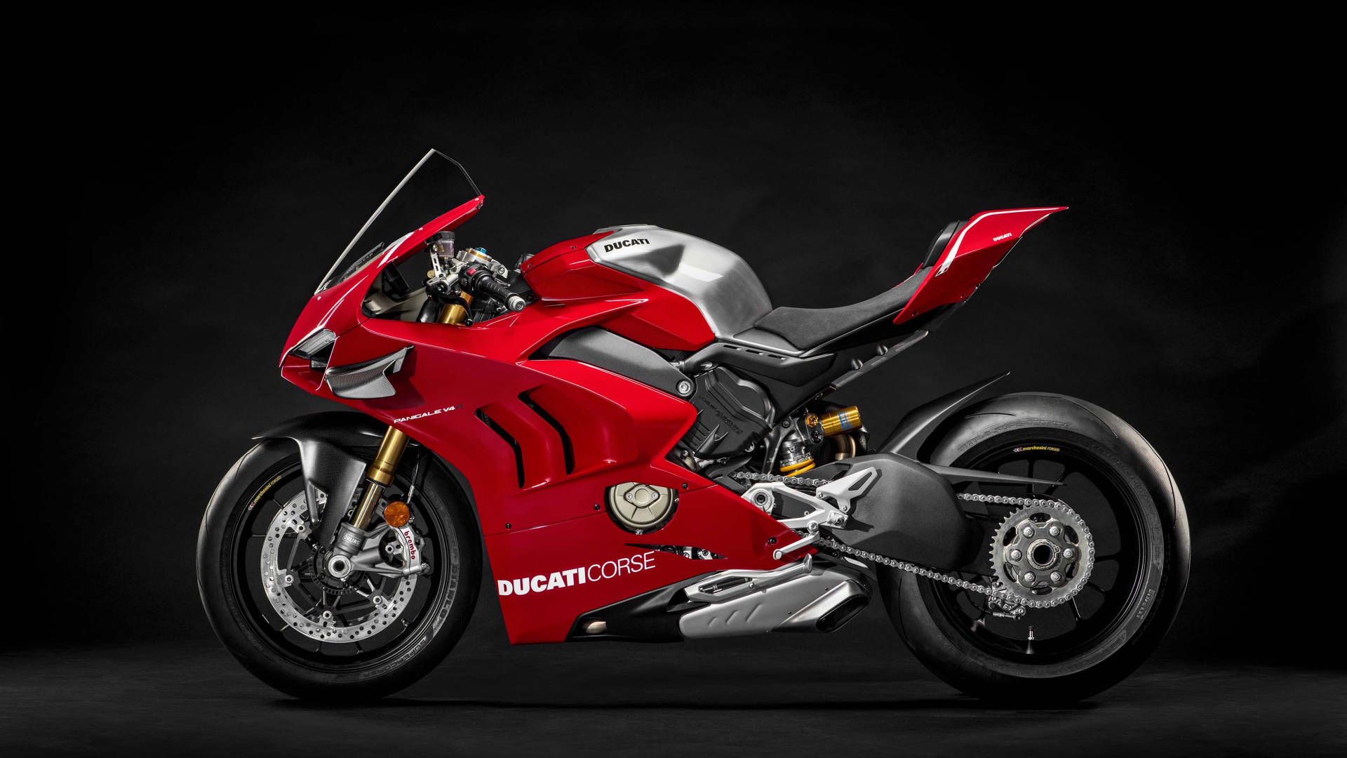紅色Ducati Corse電單車，金色前叉和銀色飾邊，深色背景。