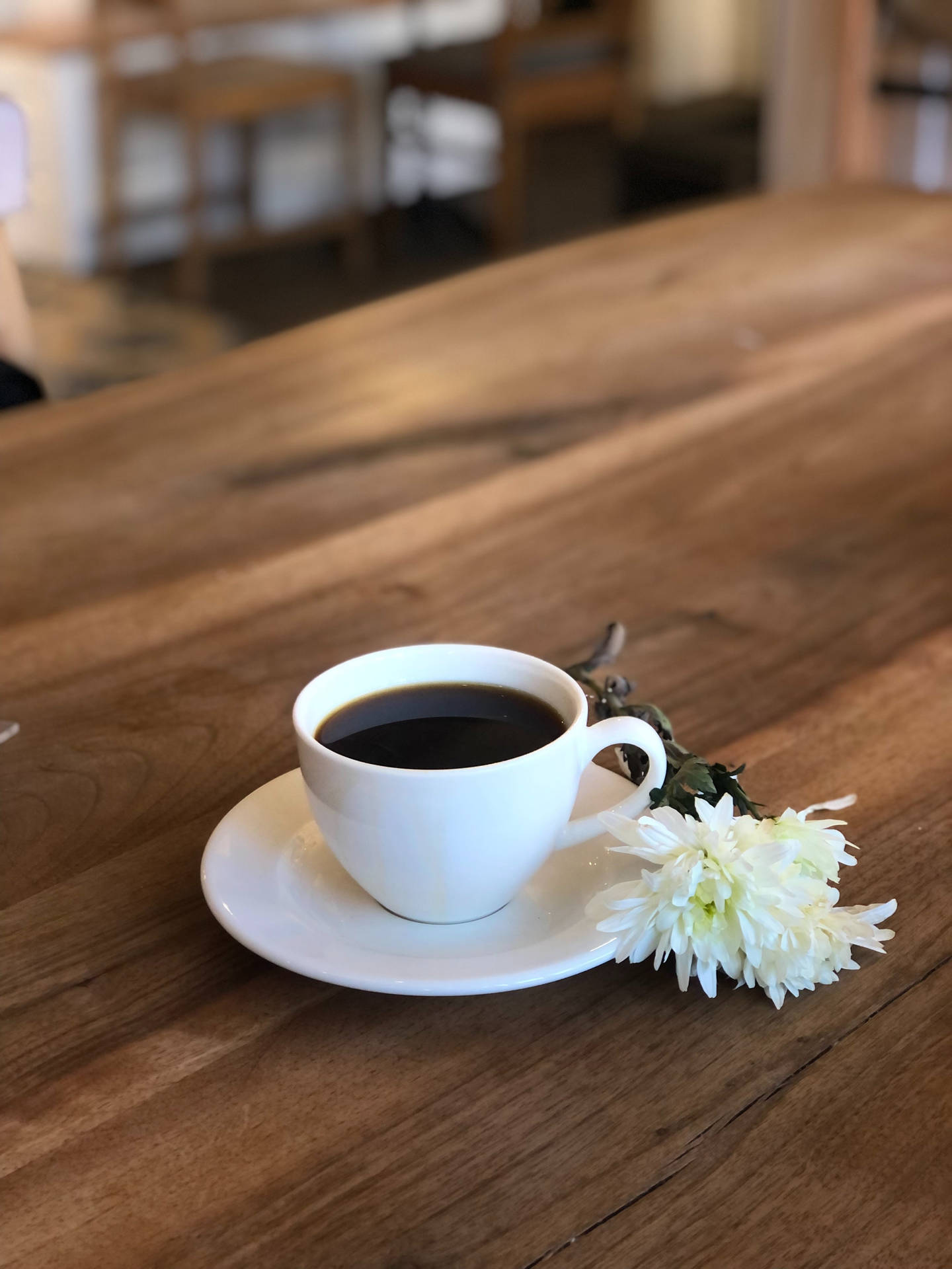 白色咖啡杯和花在咖啡館的木桌上