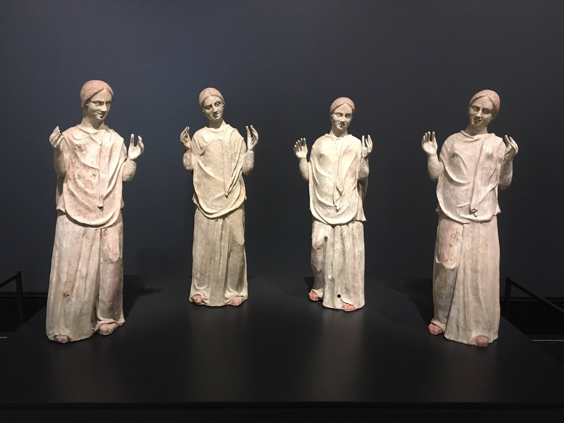 四個身穿長袍、舉起雙手的相同古代雕像在博物館展出。