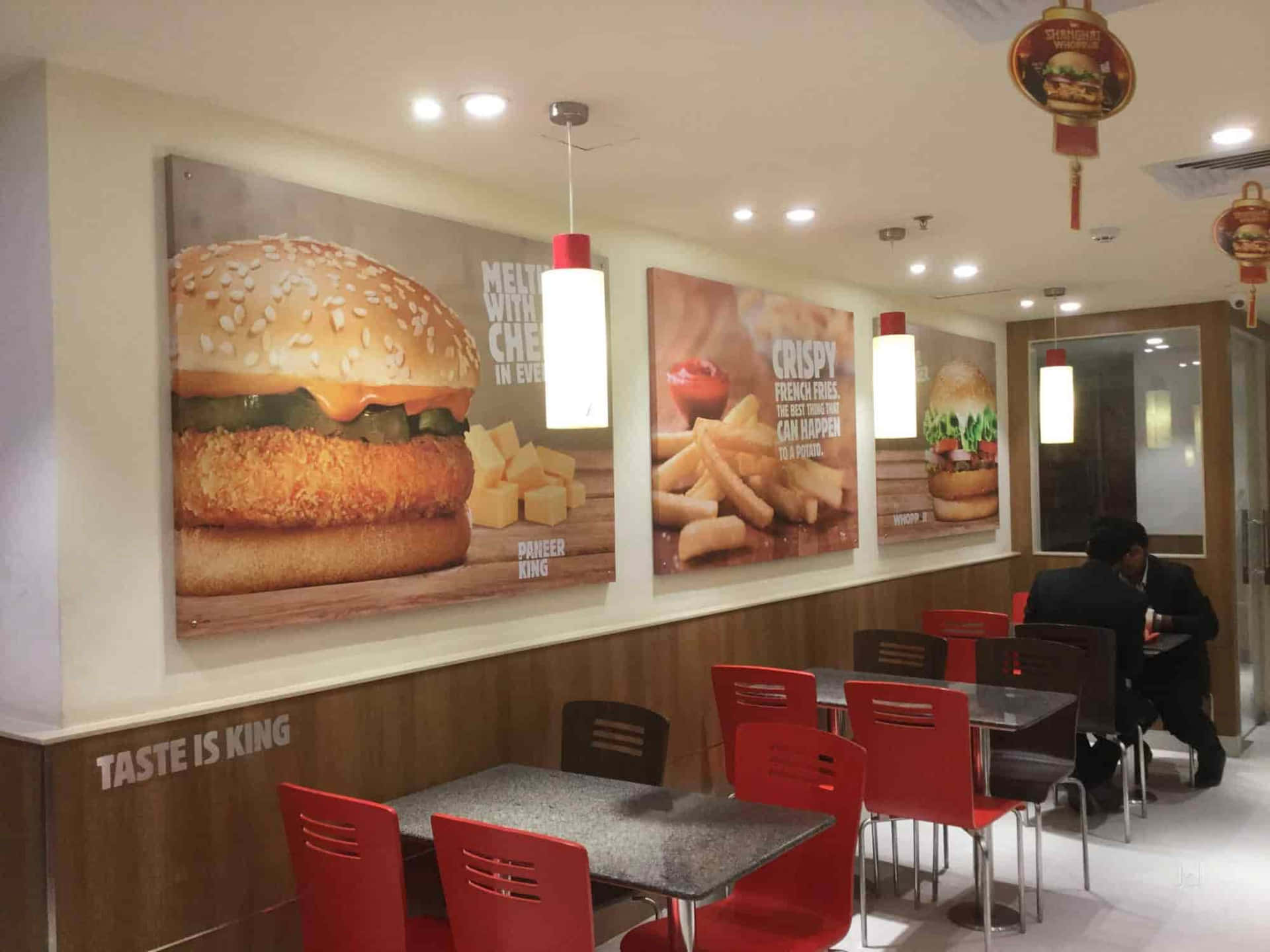 快餐店內有紅色椅子和牆上大型食物海報。