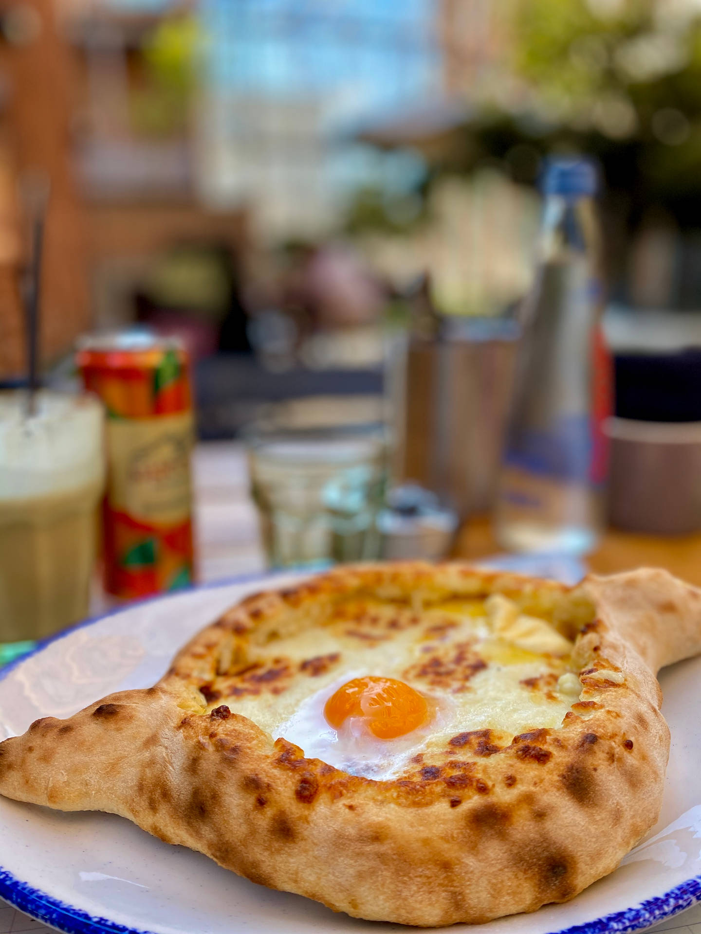藍邊白碟上的 khachapuri 配流心蛋黃，在戶外桌上。