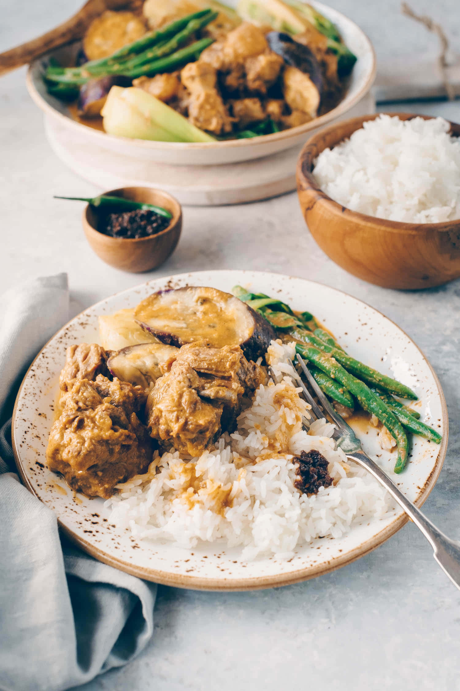 品嚐正宗菲律賓咖喱牛尾湯的豐盛滋味 壁紙 — 一盤鄉村風味的奶油咖哩，配以茄子和青豆，放在白飯上，附上香料。