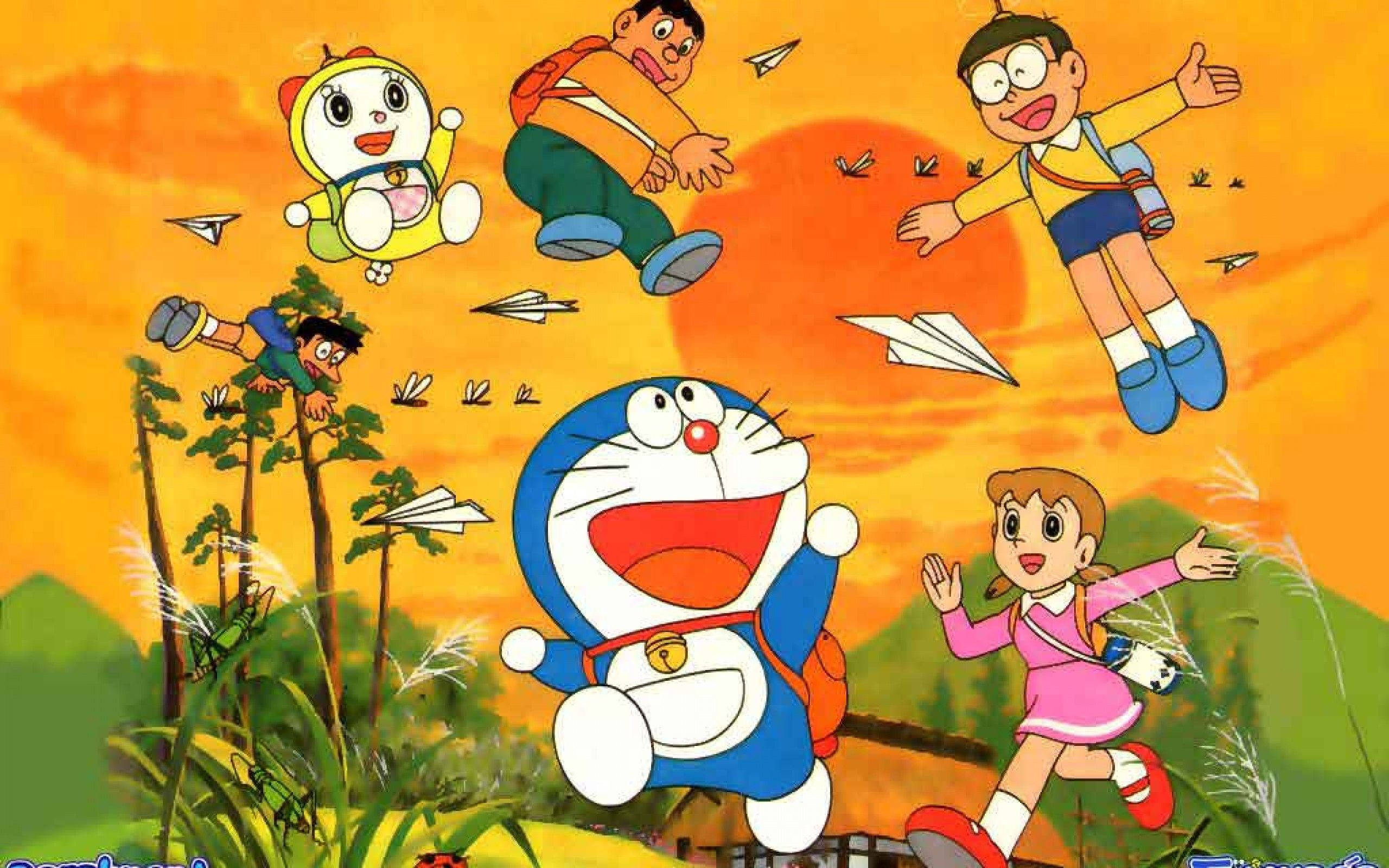 哆啦A夢在夕陽下 壁紙 — 多啦A夢和朋友們在紙飛機上，歡樂地飛翔在綠色山丘上充滿活力的日落天空。