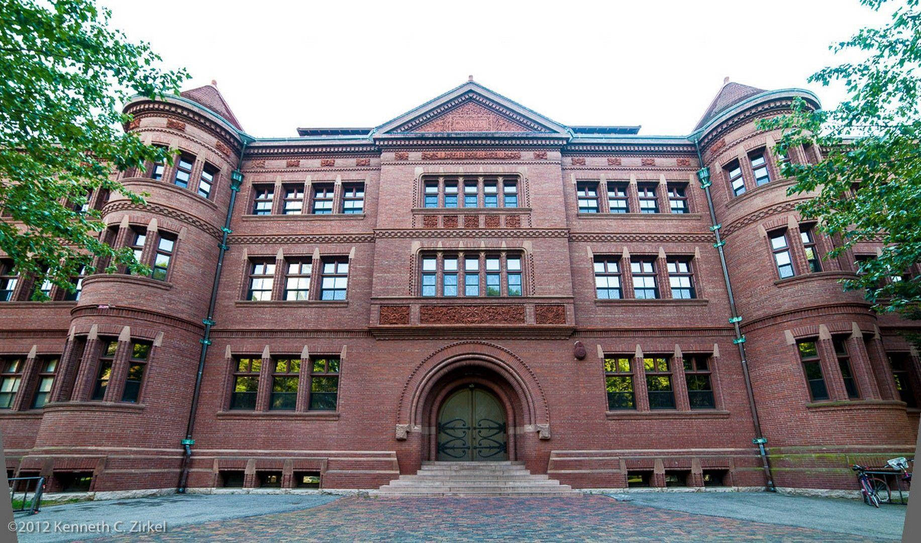 歷史悠久的紅磚大學建築，設有拱形入口和周圍樹木。