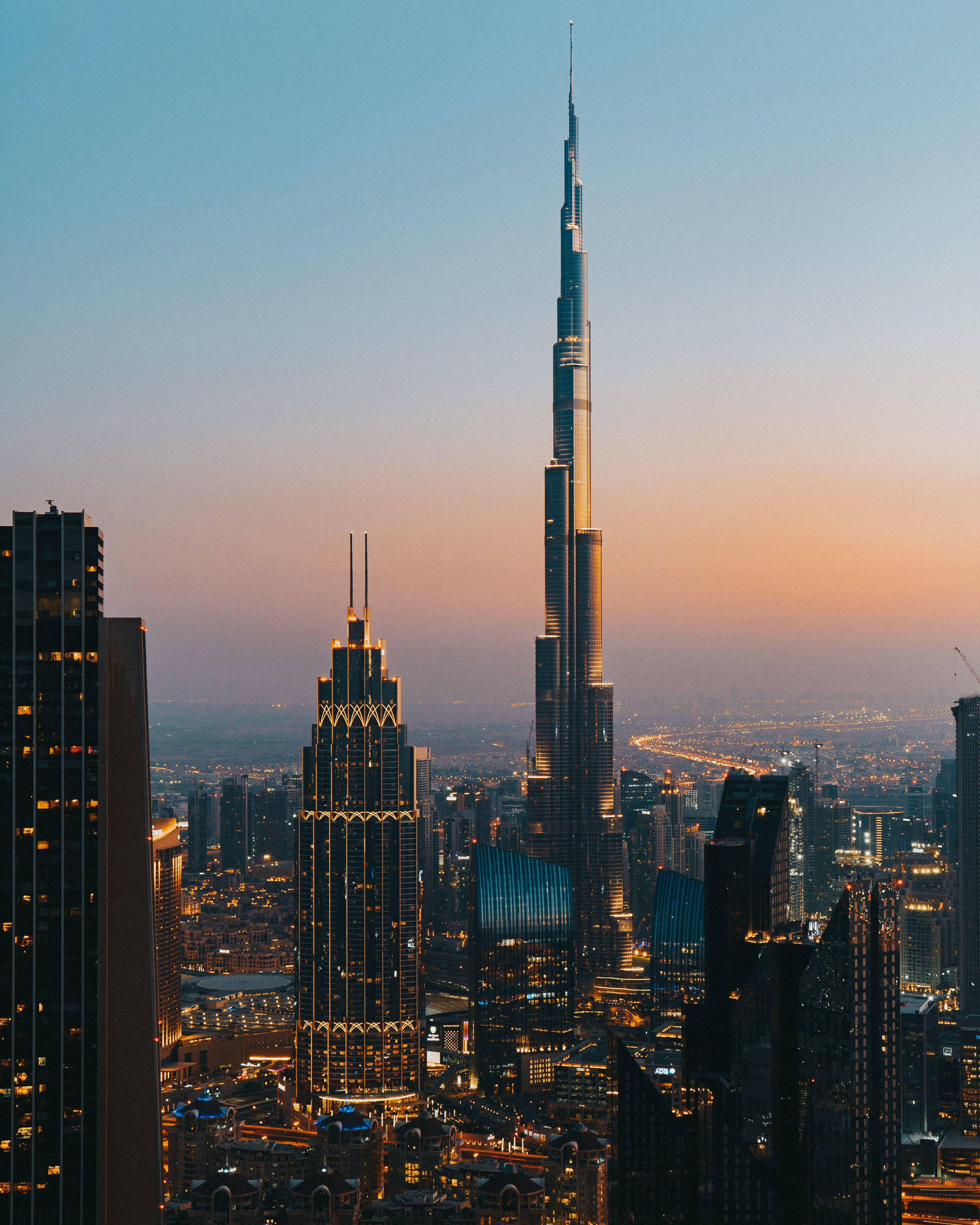 Skyscraper 桌布 壁紙 — 哈利法塔在日落時分聳立於杜拜天際線之上，金色燈光在漸變的天空中閃耀。