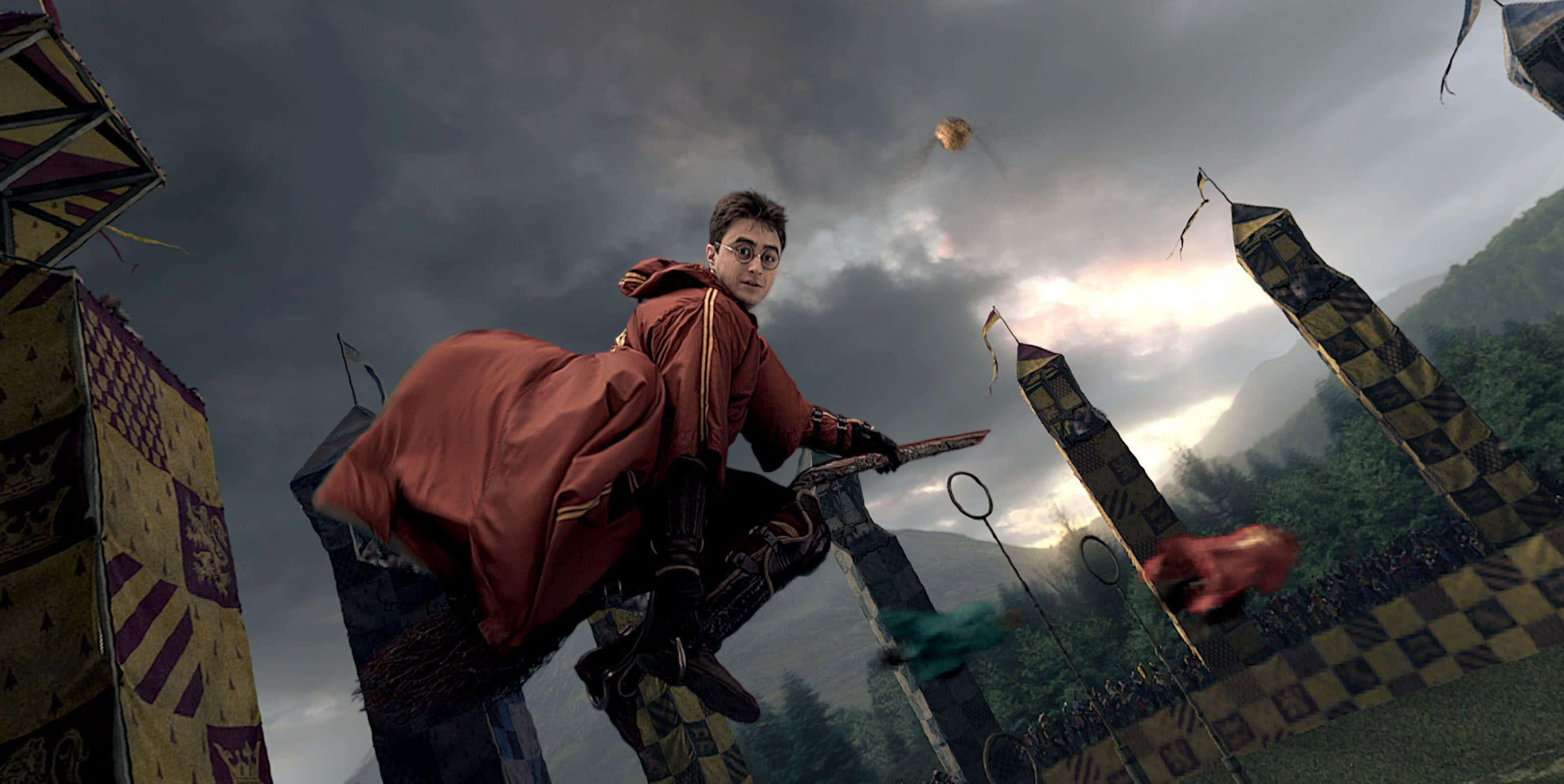 The Hogwarts Quidditch Team 桌布 壁紙 — 哈利波特在魁地奇比賽中騎著掃帚飛過暴風雨的天空，伴隨著飛舞的圓環和旗幟。
