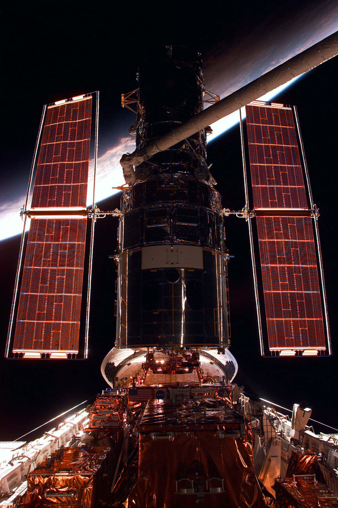 Hubble Space Telescope 桌布 壁紙 — 哈勃太空望远镜在漆黑的太空中闪耀着温暖的橙色太阳能板，背后是地球弯曲的地平线在发光。