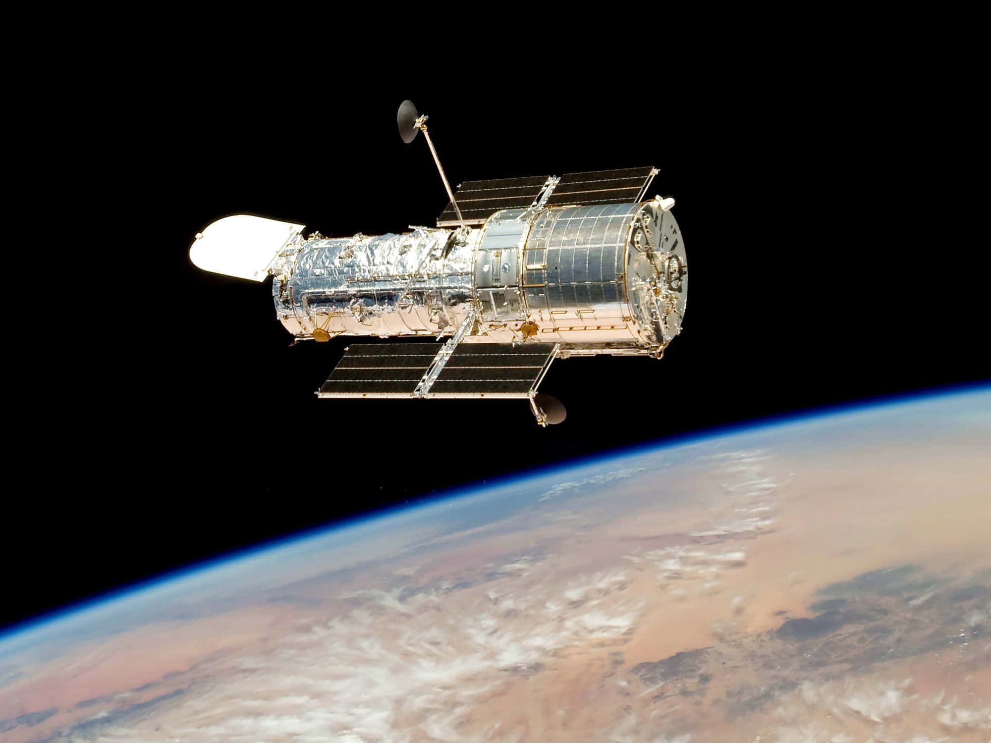 Hubble Space Telescope 桌布 壁紙 — 哈勃太空望遠鏡在太空的漆黑背景下，滑過地球彎曲的地平線。