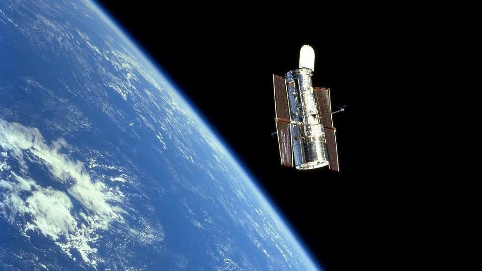Hubble Space Telescope 桌布 壁紙 — 哈勃太空望遠鏡在漆黑的太空中繞地球運行，藍色行星在下方彎曲。