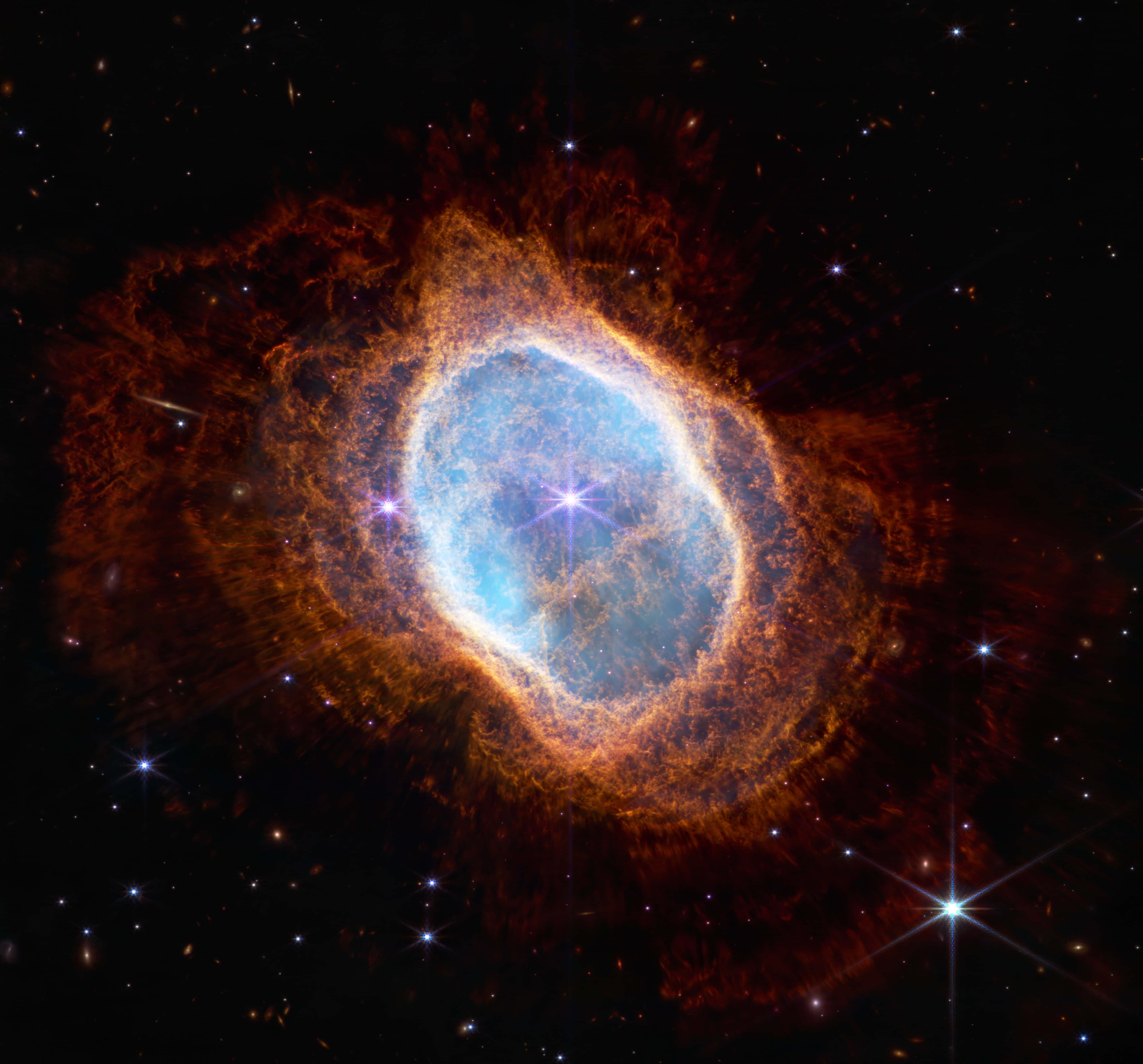 哈勃太空望遠鏡捕捉的宇宙奇景 壁紙 — 一個充滿活力的宇宙星雲，中心發出藍色光芒，被熾熱的橙色觸手環繞，背景是星空。