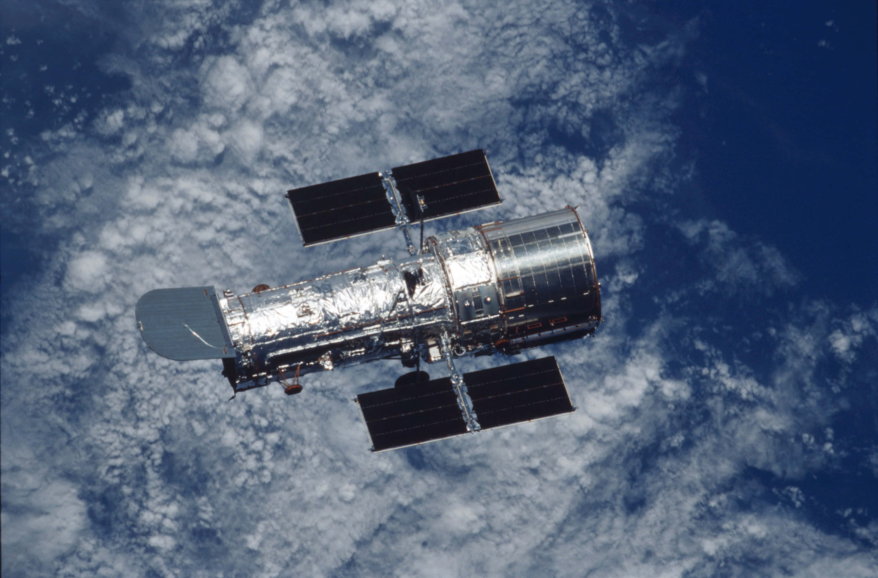 Hubble Space Telescope 桌布 壁紙 — 哈勃太空望遠鏡漂浮在藍白雲層覆蓋的地球表面之上。