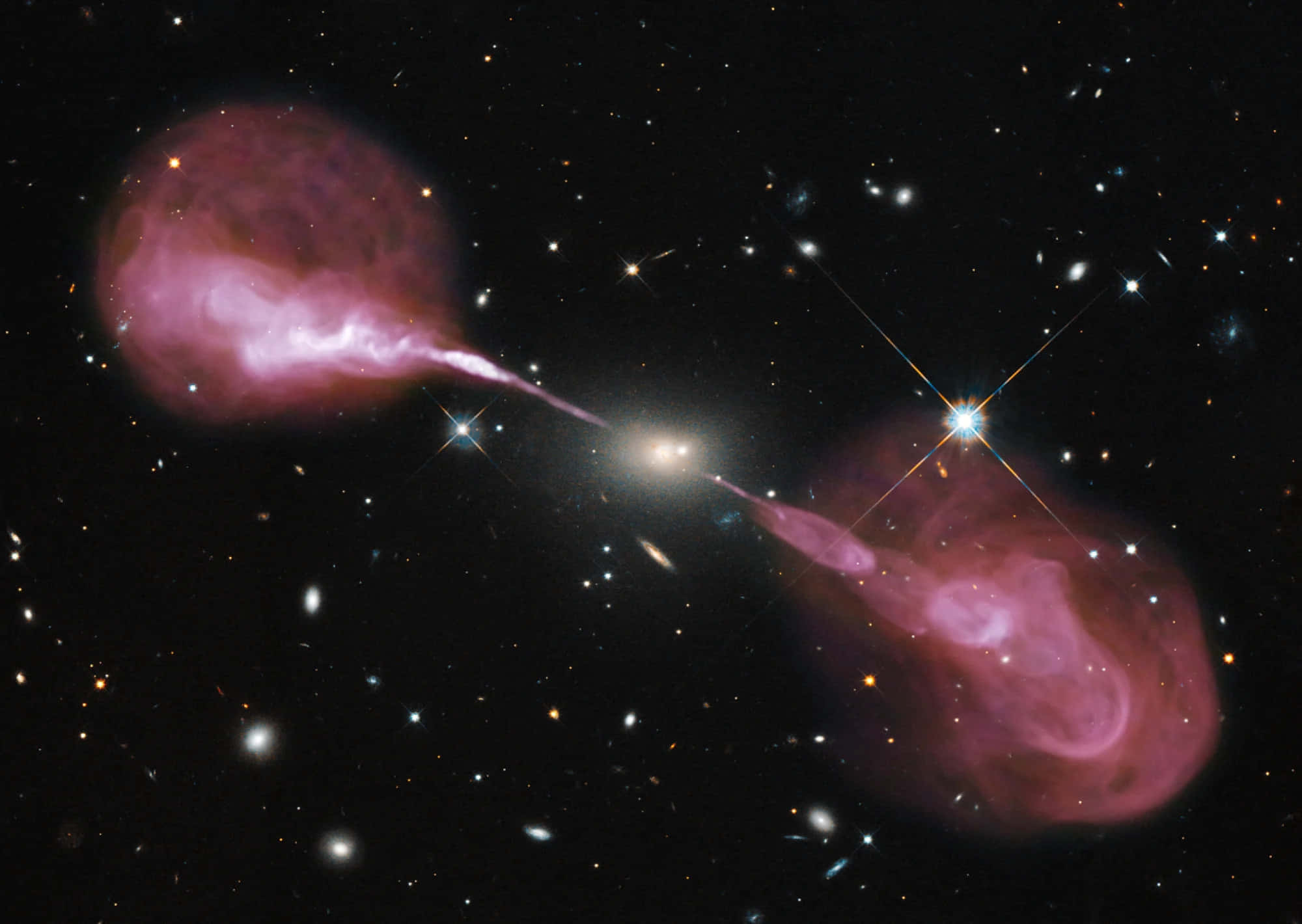 哈勃望遠鏡揭開橢圓星系NGC 4889中心黑洞的壯觀近照 壁紙 — 星系的宇宙碰撞在星空背景下發出充滿活力的粉紅色噴流。