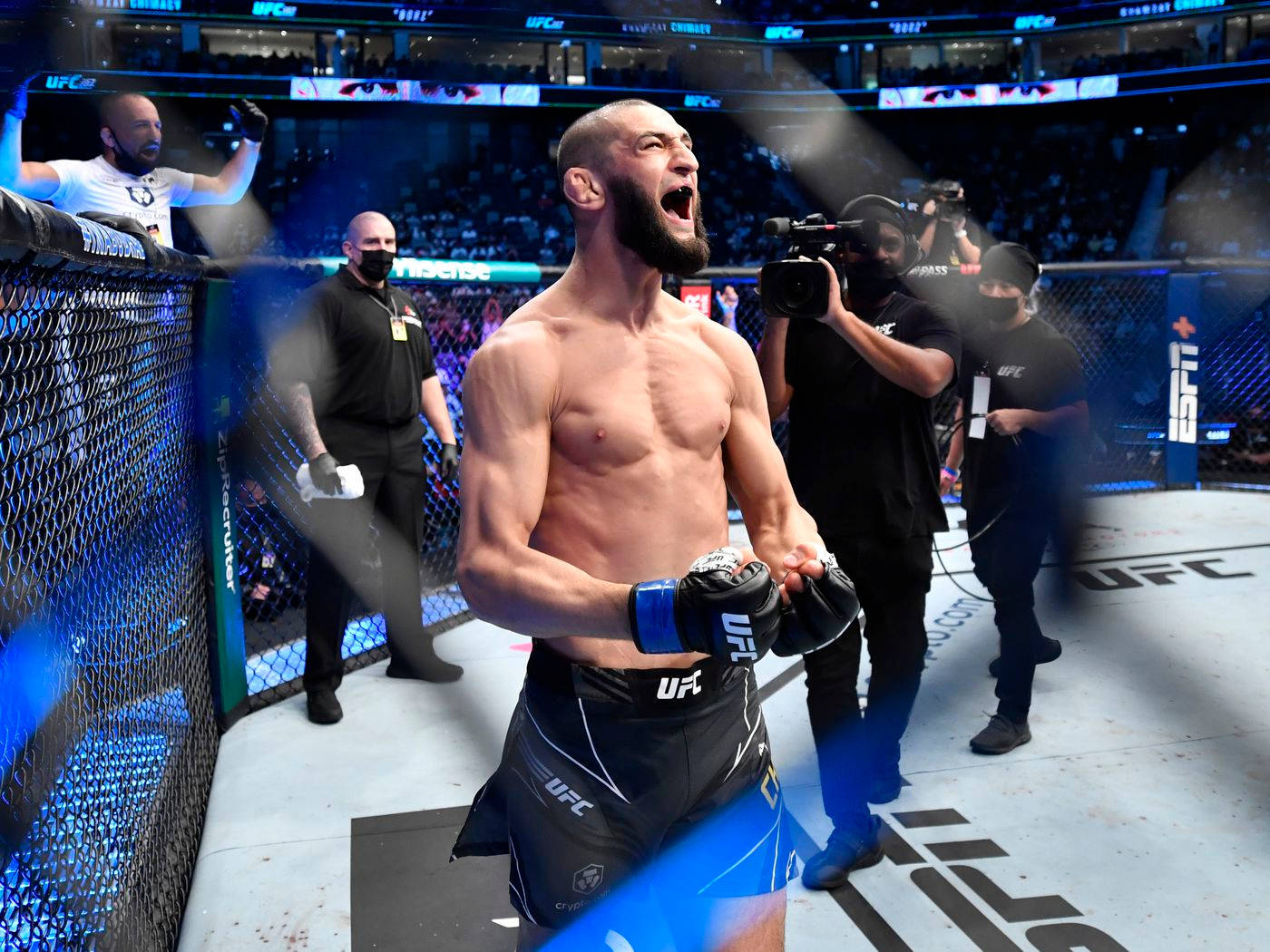 UFC拳手在八角籠內慶祝勝利，背景有煙霧和人群。