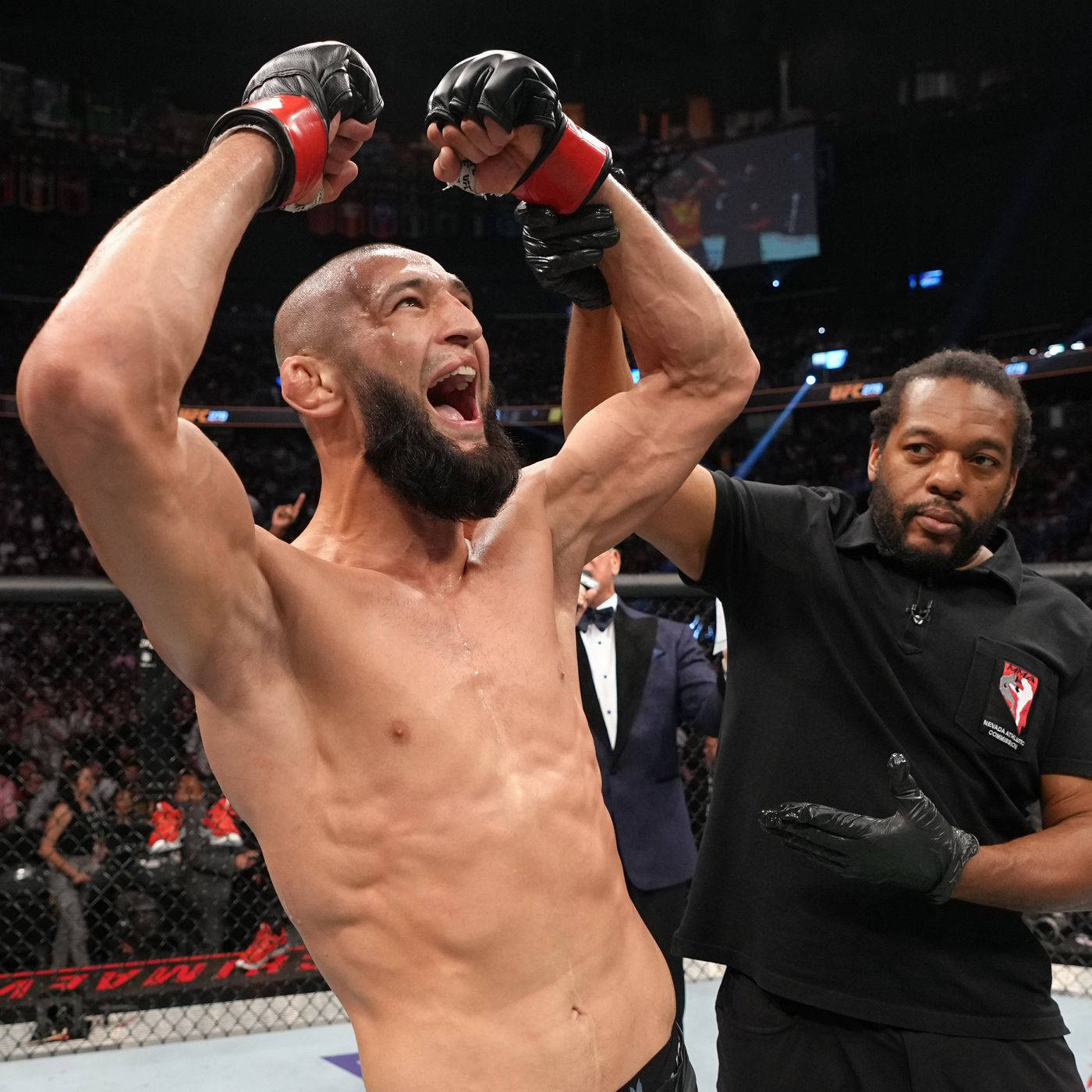 MMA拳手在八角籠內與裁判一起慶祝勝利。