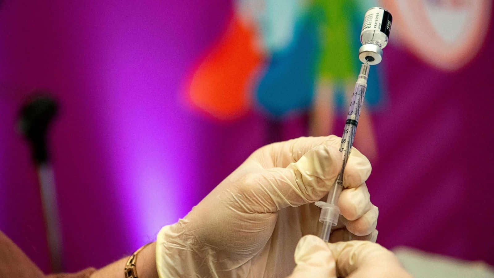 戴手套的手將疫苗吸入注射器以備醫療用途。