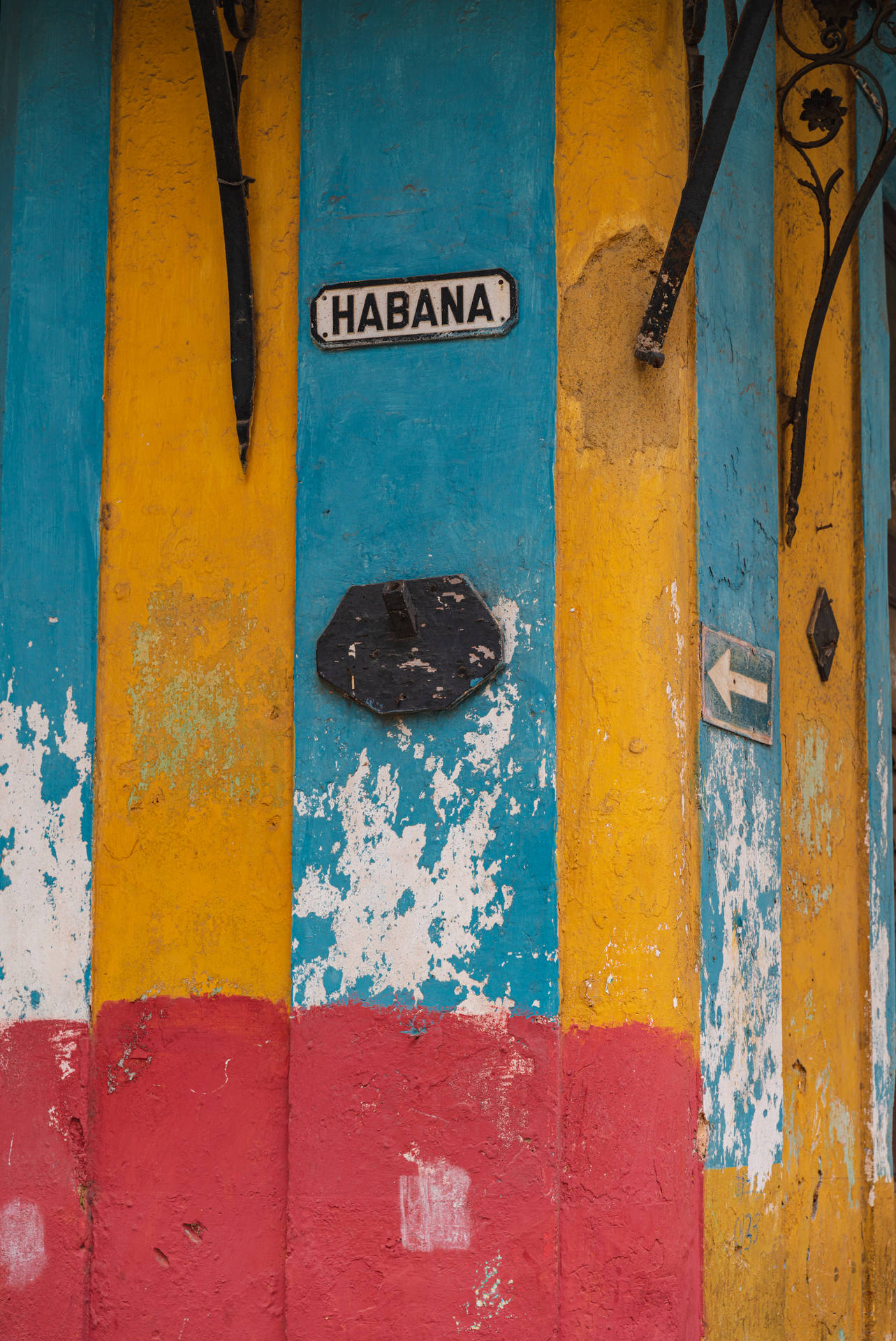 色彩繽紛的風化木門，帶有「HABANA」標誌和黑色金屬裝飾。