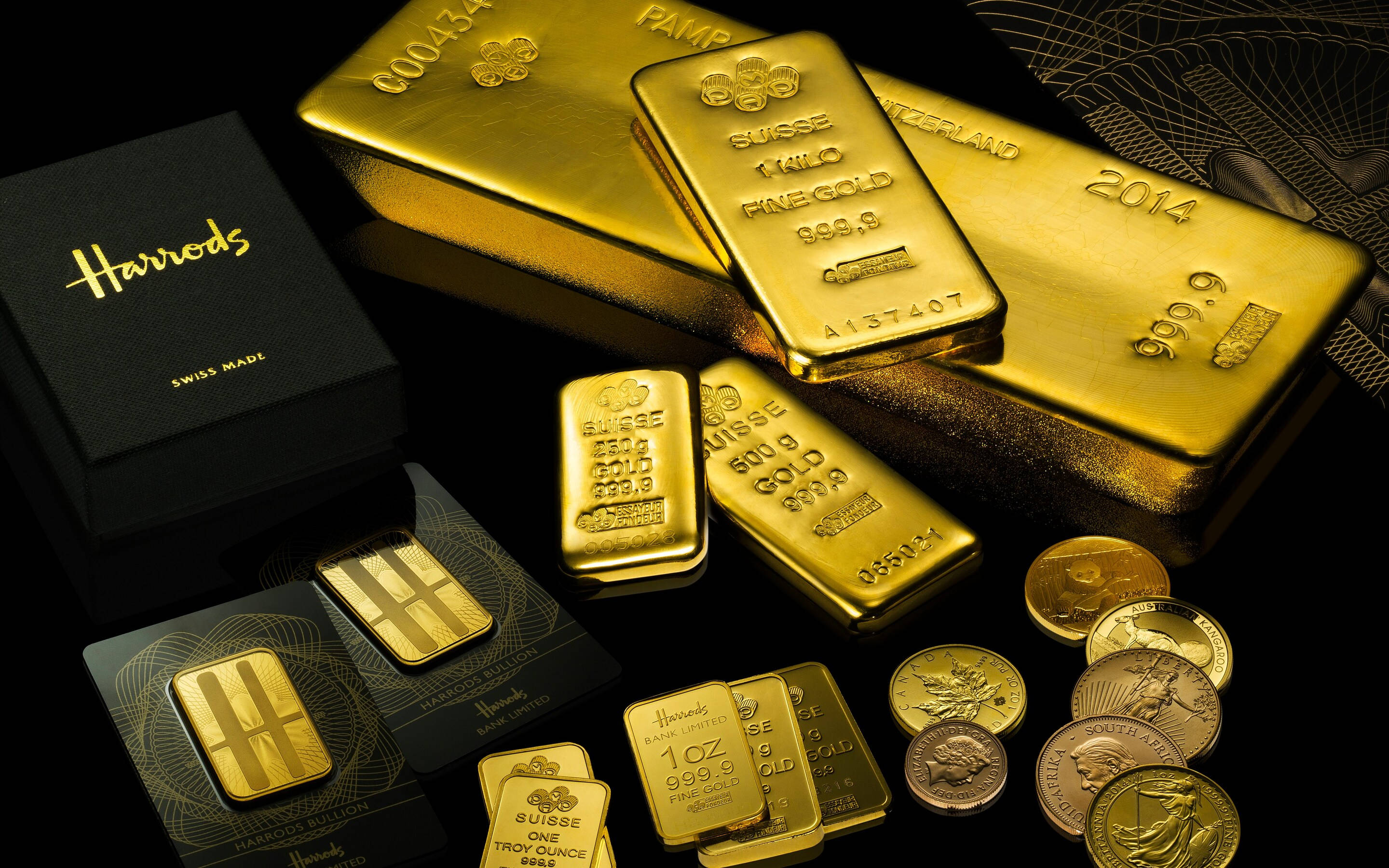 哈羅德專屬金條收藏 壁紙 — 閃亮的金條和金幣排列在黑色表面上，附近有一個 Harrods 品牌盒子。