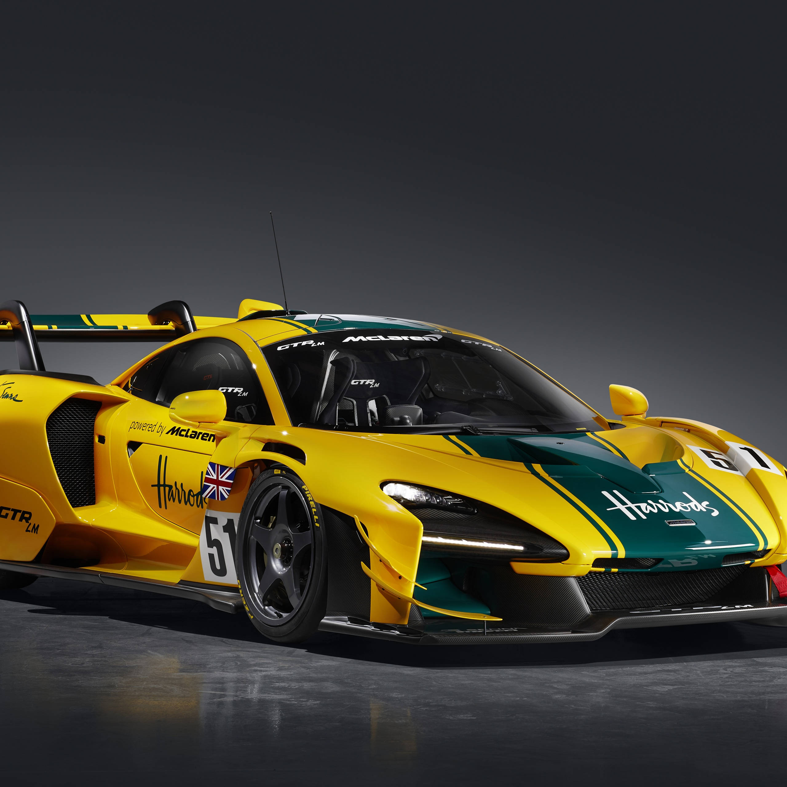 哈羅德百貨前的麥拉倫塞納 壁紙 — 一輛鮮豔的黃綠色McLaren Senna GTR LM賽車，編號51，帶有Harrods品牌標誌，在黑暗的攝影棚中擺拍。