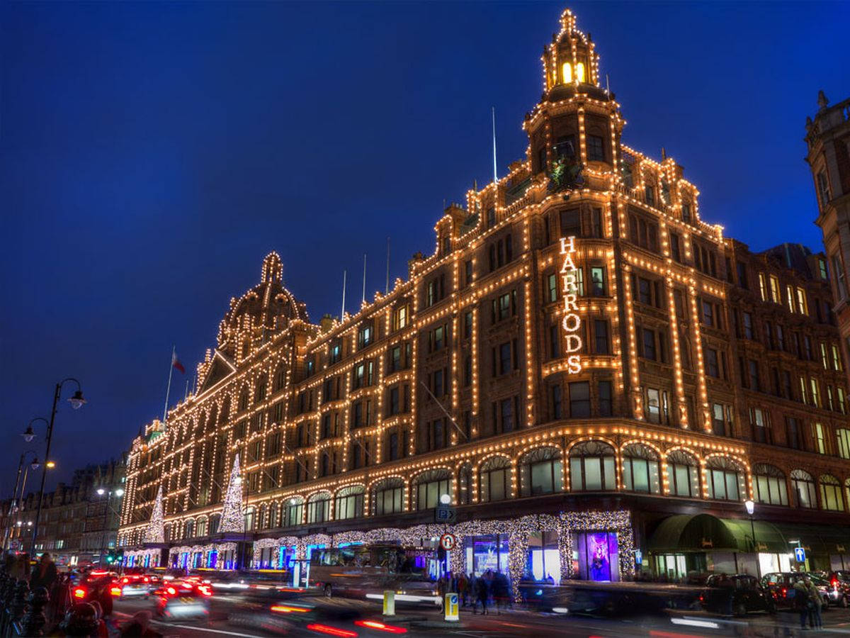 哈羅德百貨夜景城市燈光 壁紙 — Harrods 百貨公司在深藍色夜空下閃耀著金色燈光，模糊的汽車燈光掠過。
