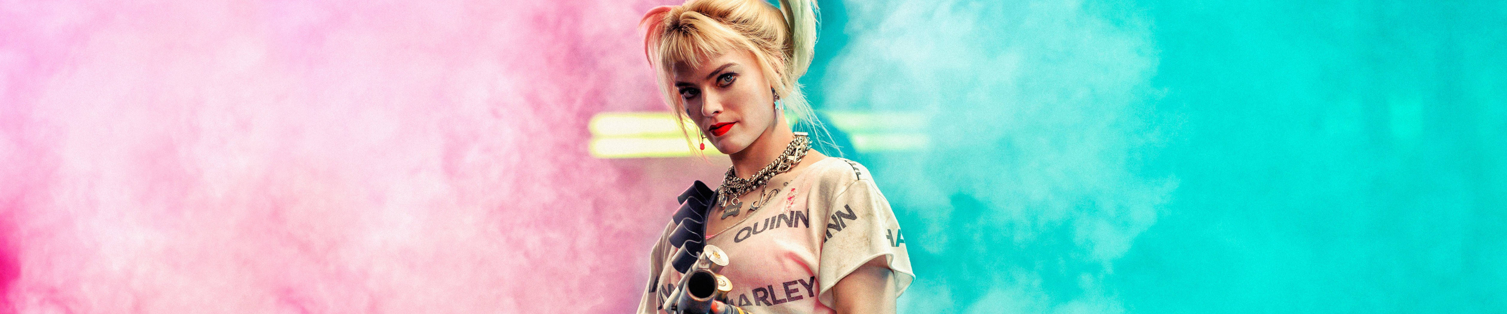 金髮女子穿著 Harley Quinn 襯衫，置身於粉紅色和藍綠色煙霧中。