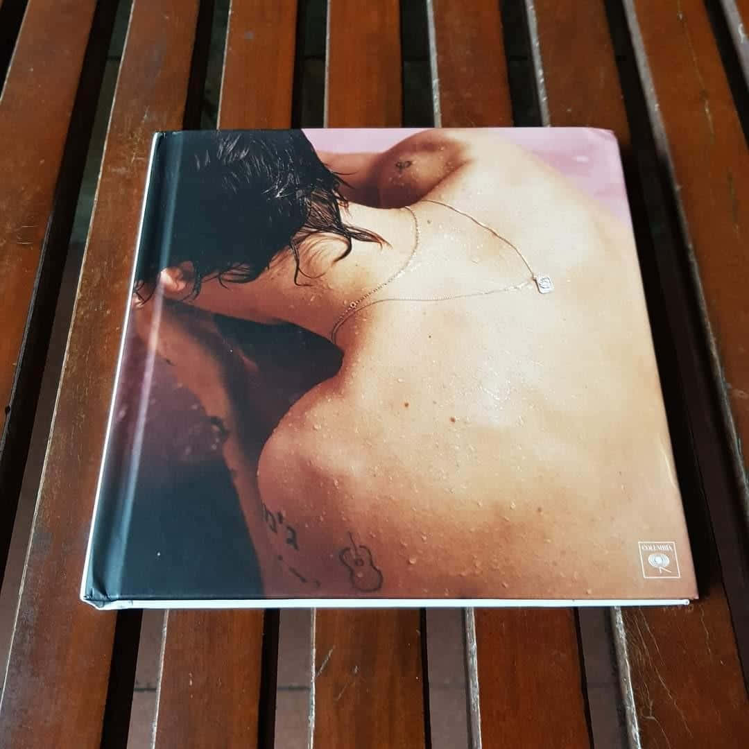 專輯封面顯示一個濕背，帶有結他紋身和希伯來文，在木凳上。