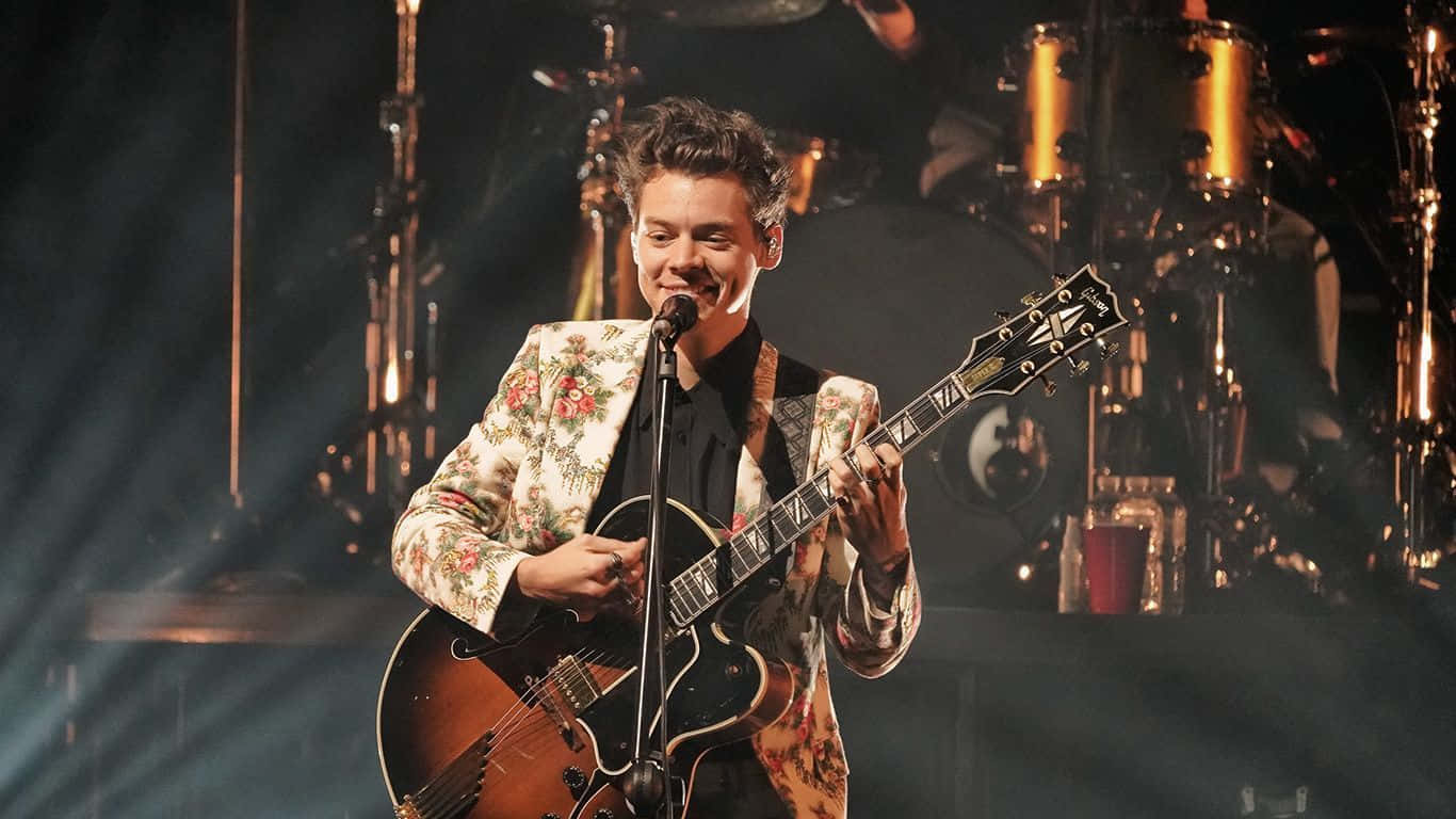 Harry Styles 在現場音樂會表演中於舞台上彈結他。
